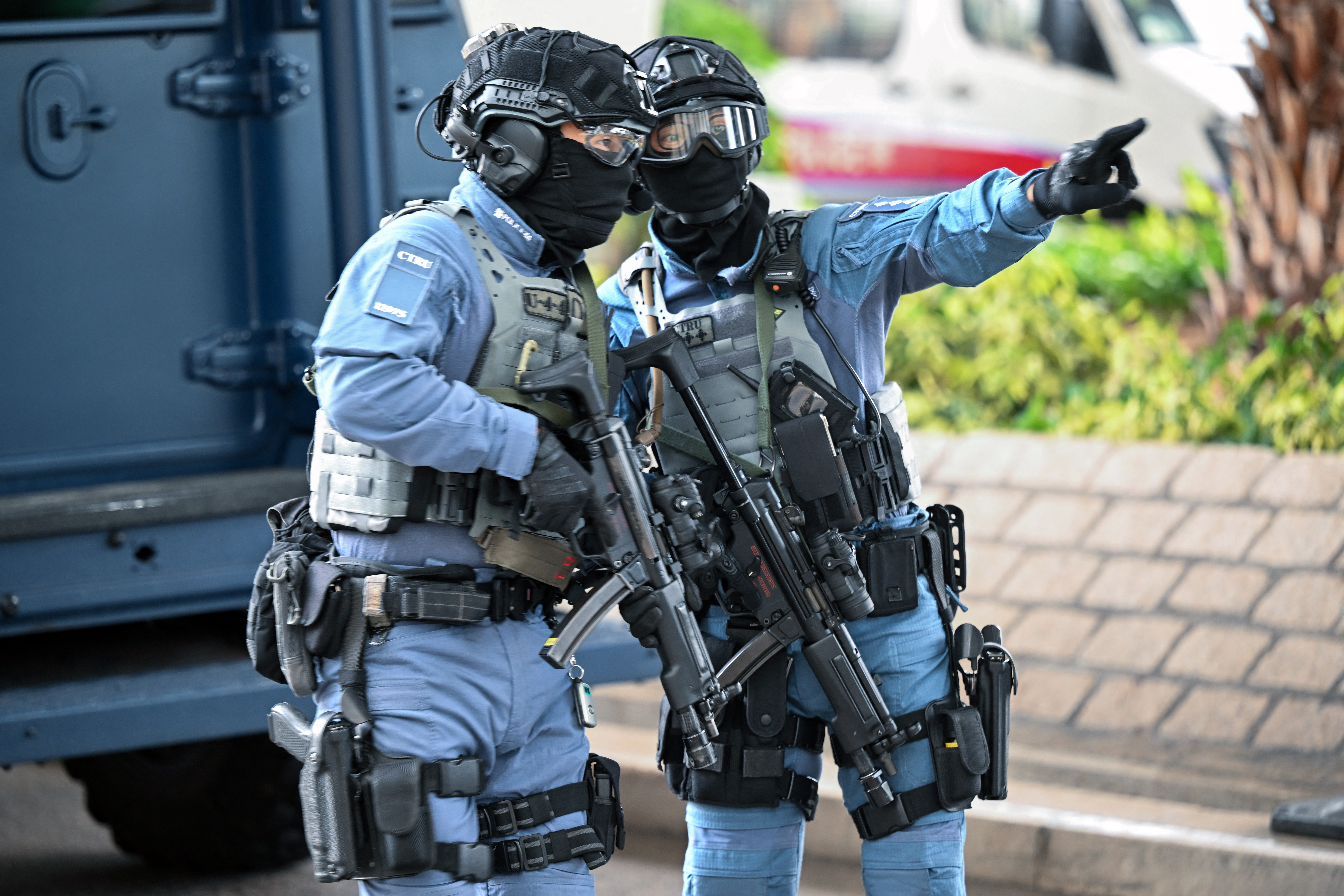 Two heavily armed police officers outside the court. They have helmets, goggles, bullet proof vests, guns strapped to their thighs and assault weapons.