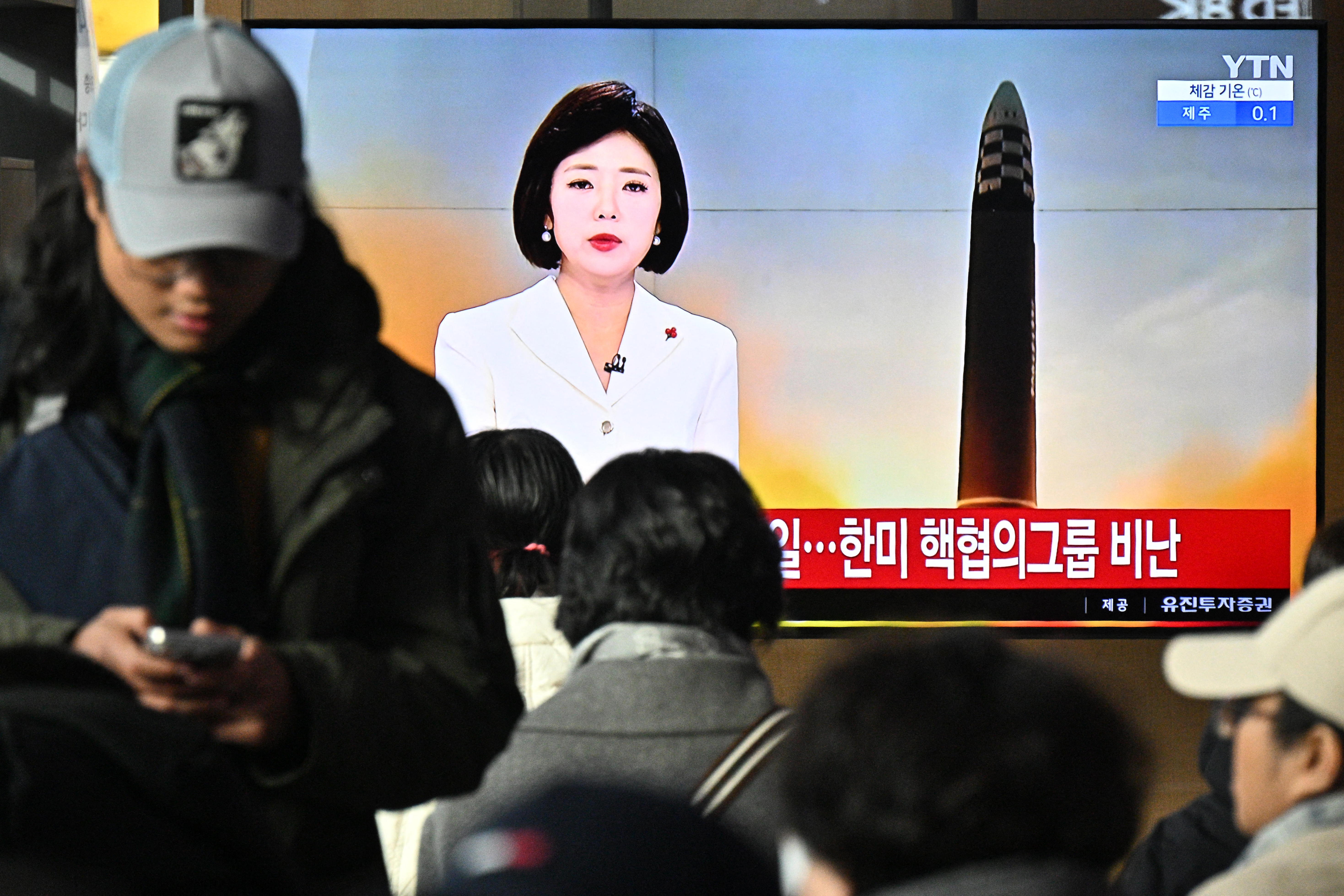 People watching a giant TV screen showing news about the North Korean missile launch