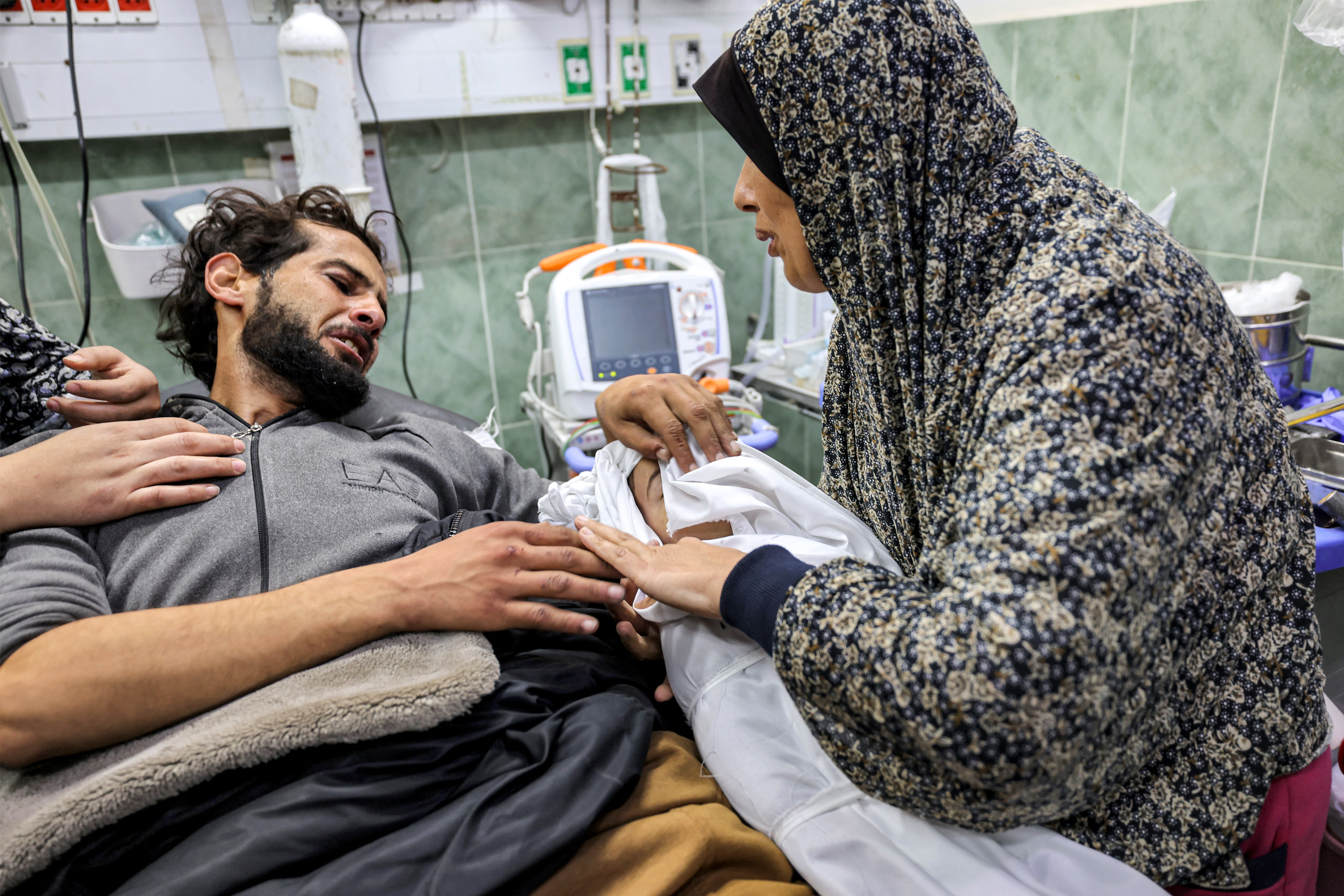 An injured man bids farewell to the body of his son as they lie in a hospital, in the afternath of overnight Israeli bombardment, in Rafah in the southern Gaza Strip.