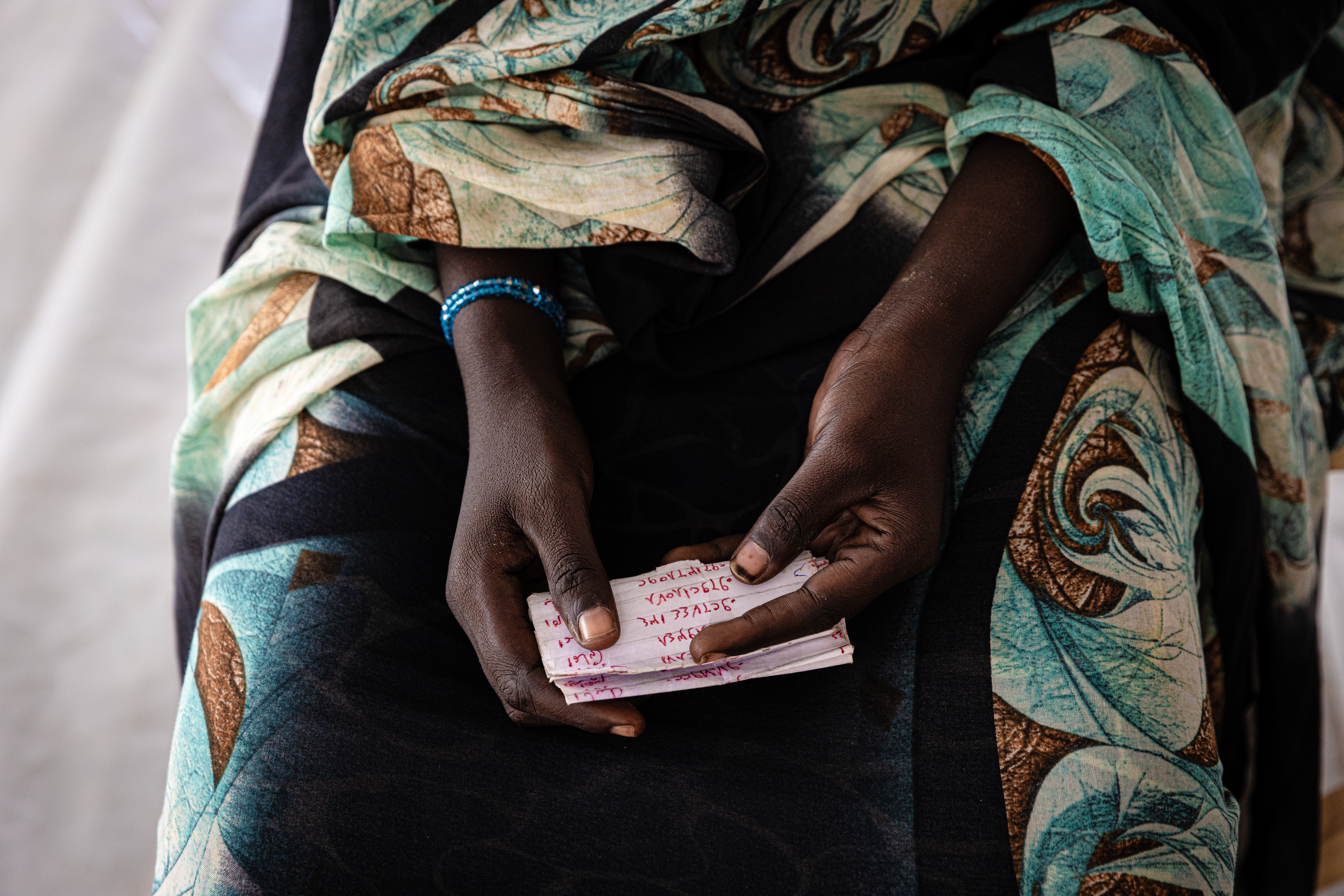 Zuhal is handing a piece of paper with her uncle’s phone number to a Red Cross volunteer. She uses Red Cross phone service to reach her uncle who lives in Gedaref, Eastern Sudan. She hopes to go live with him, but her phone calls have not gone through.