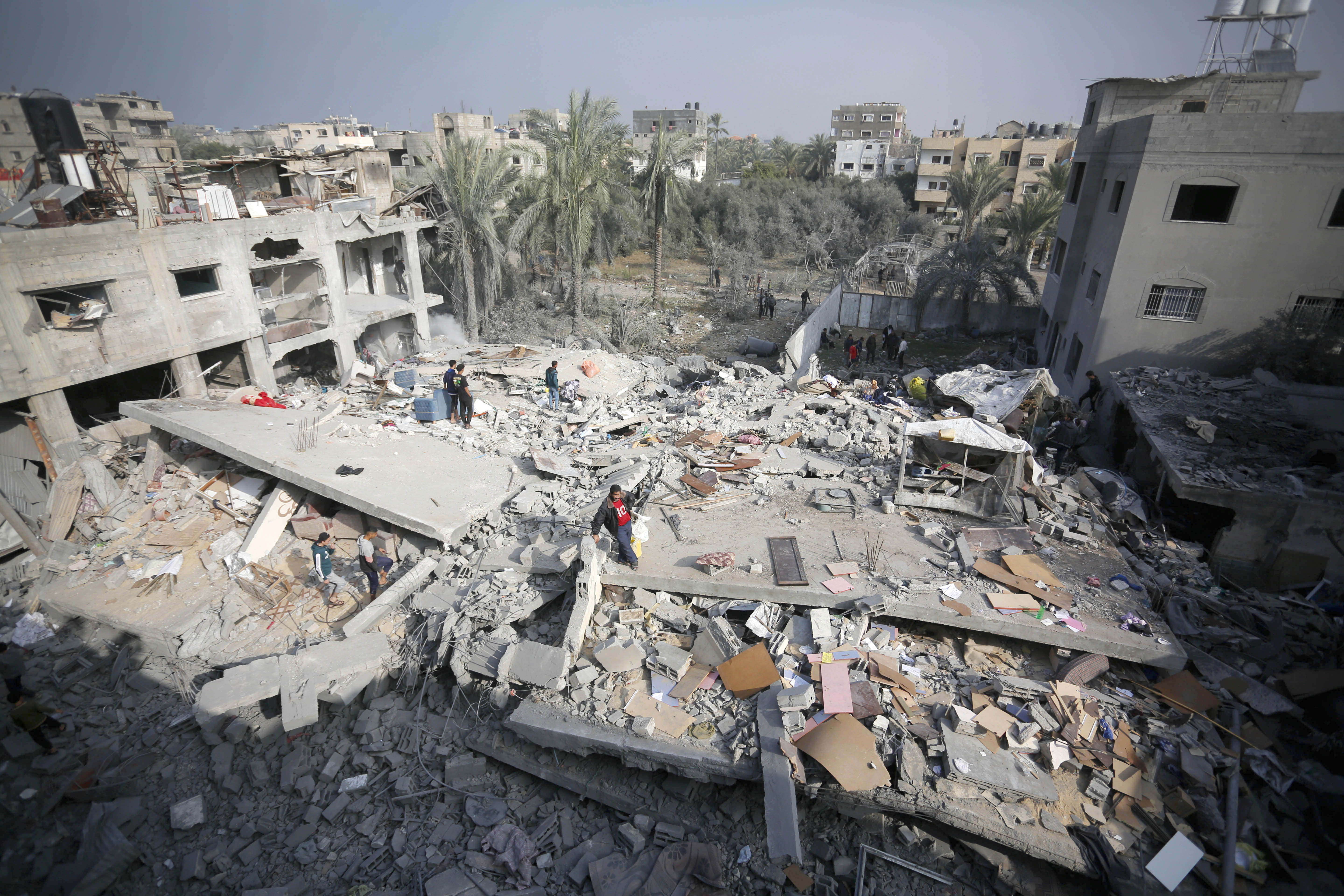 Palestinians try to collect usable items under the rubbles of a building, demolished following the Israeli attacks, in Deir al-Balah, Gaza on December 12