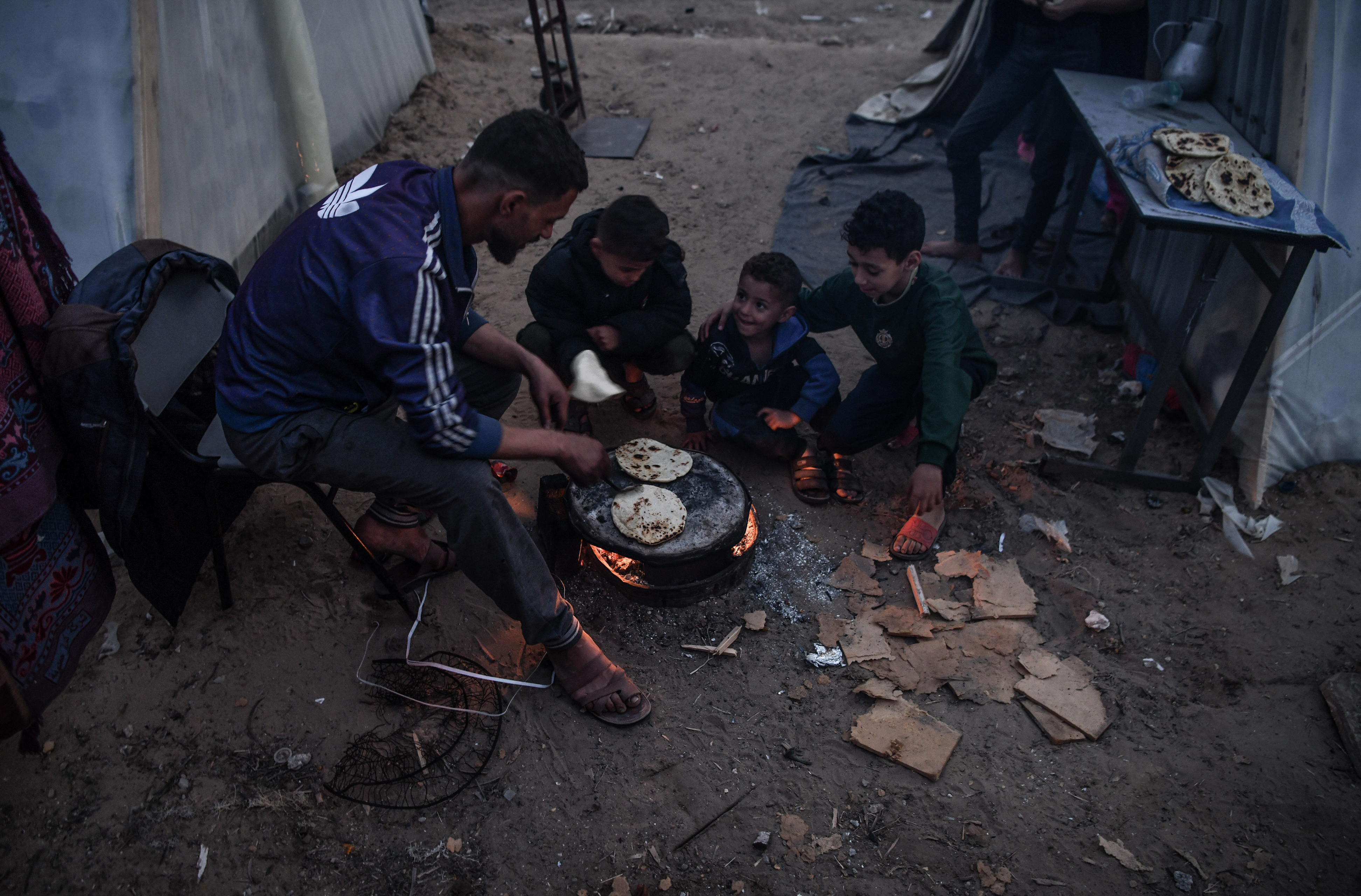Palestinians cook around their makeshift tents as they left their homes and took refuge in Rafah city in order to protect themselves from Israeli attacks and to ensure their safety in Rafah.