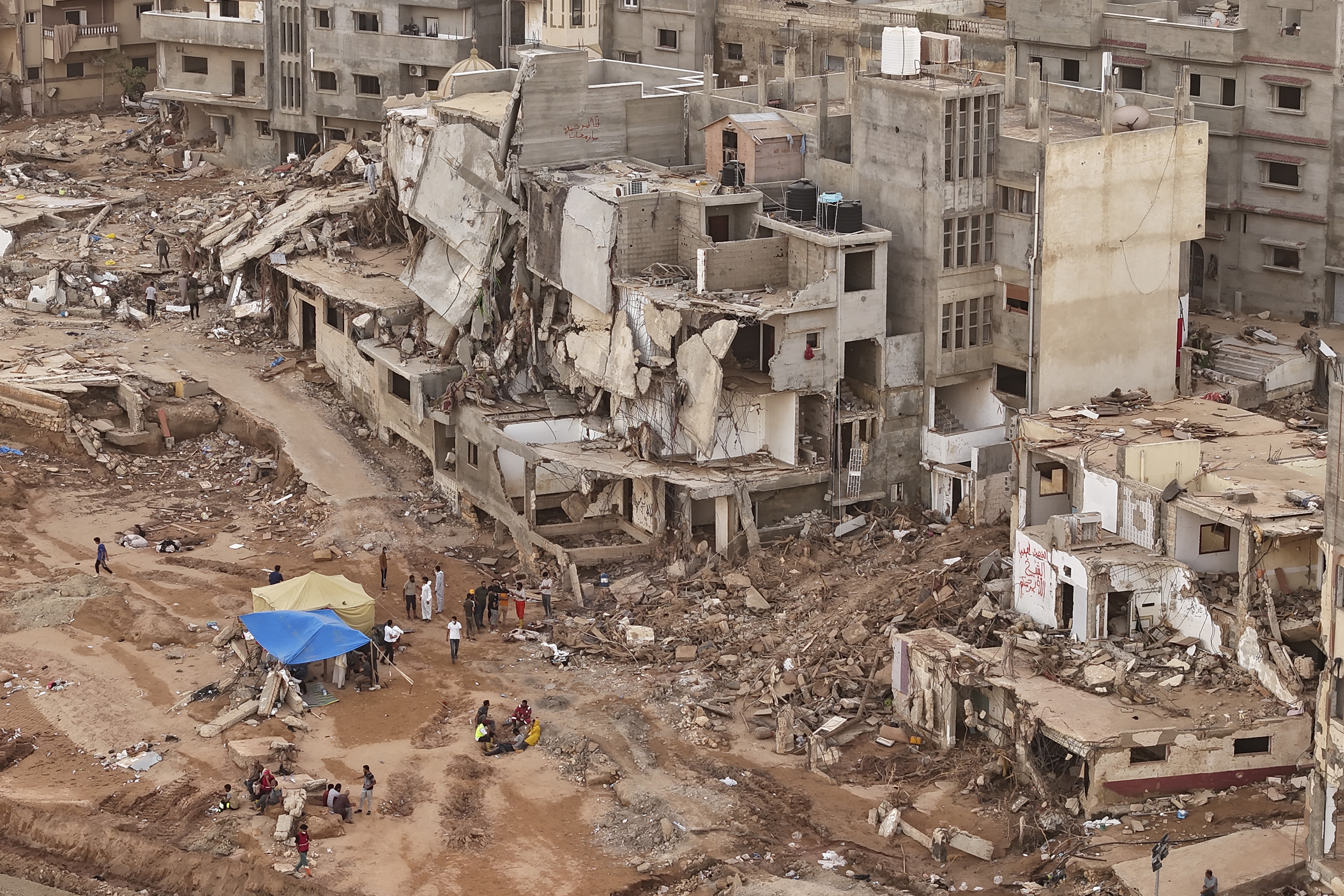 Rescuers and relatives sit in front of collapsed buildings after recent flooding caused by Mediterranean storm Daniel, in Derna, Libya.