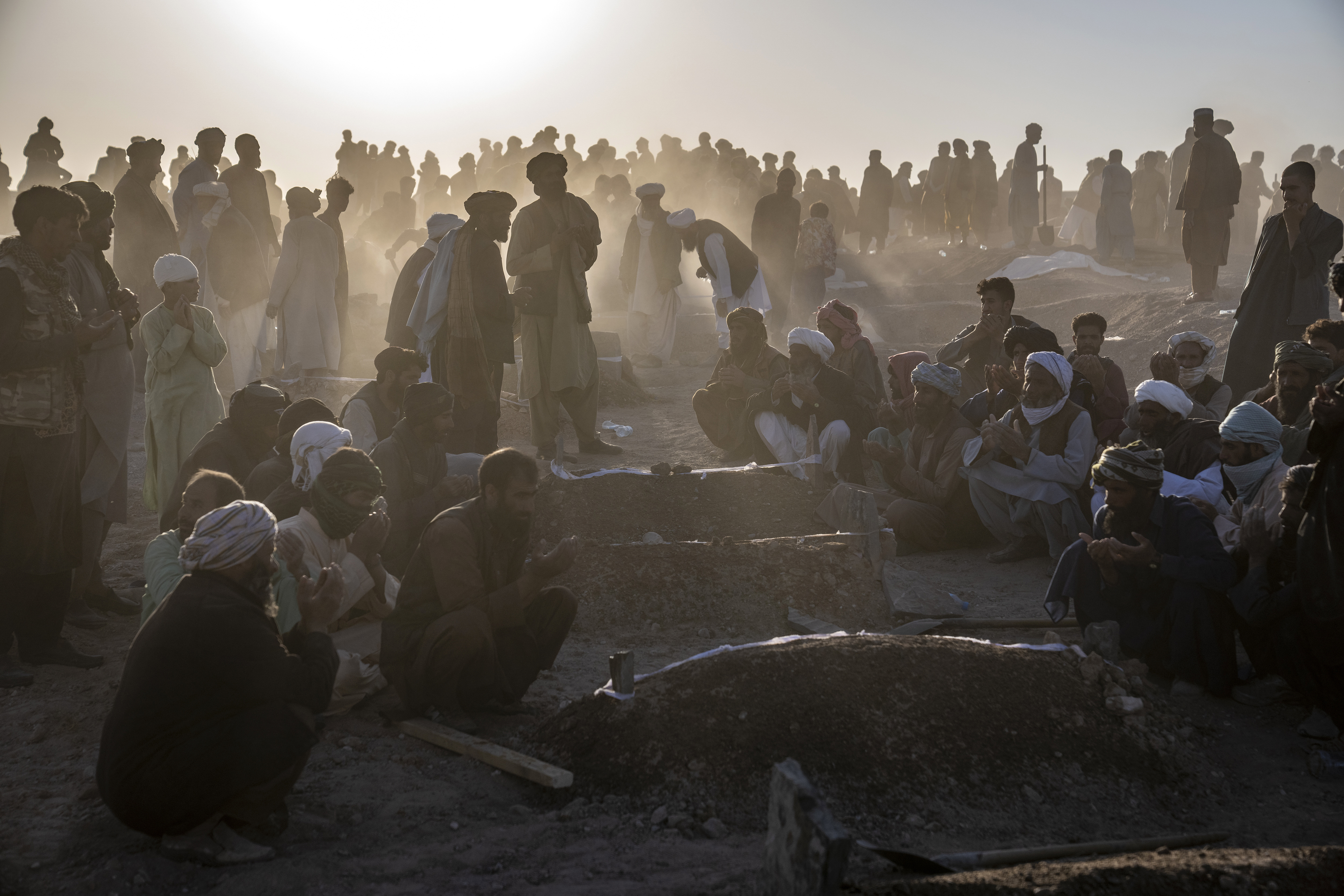 Afghans bury hundreds of people killed in an earthquake to a burial site, in a village in Zenda Jan district in Herat province, western of Afghanistan, Monday, Oct. 9