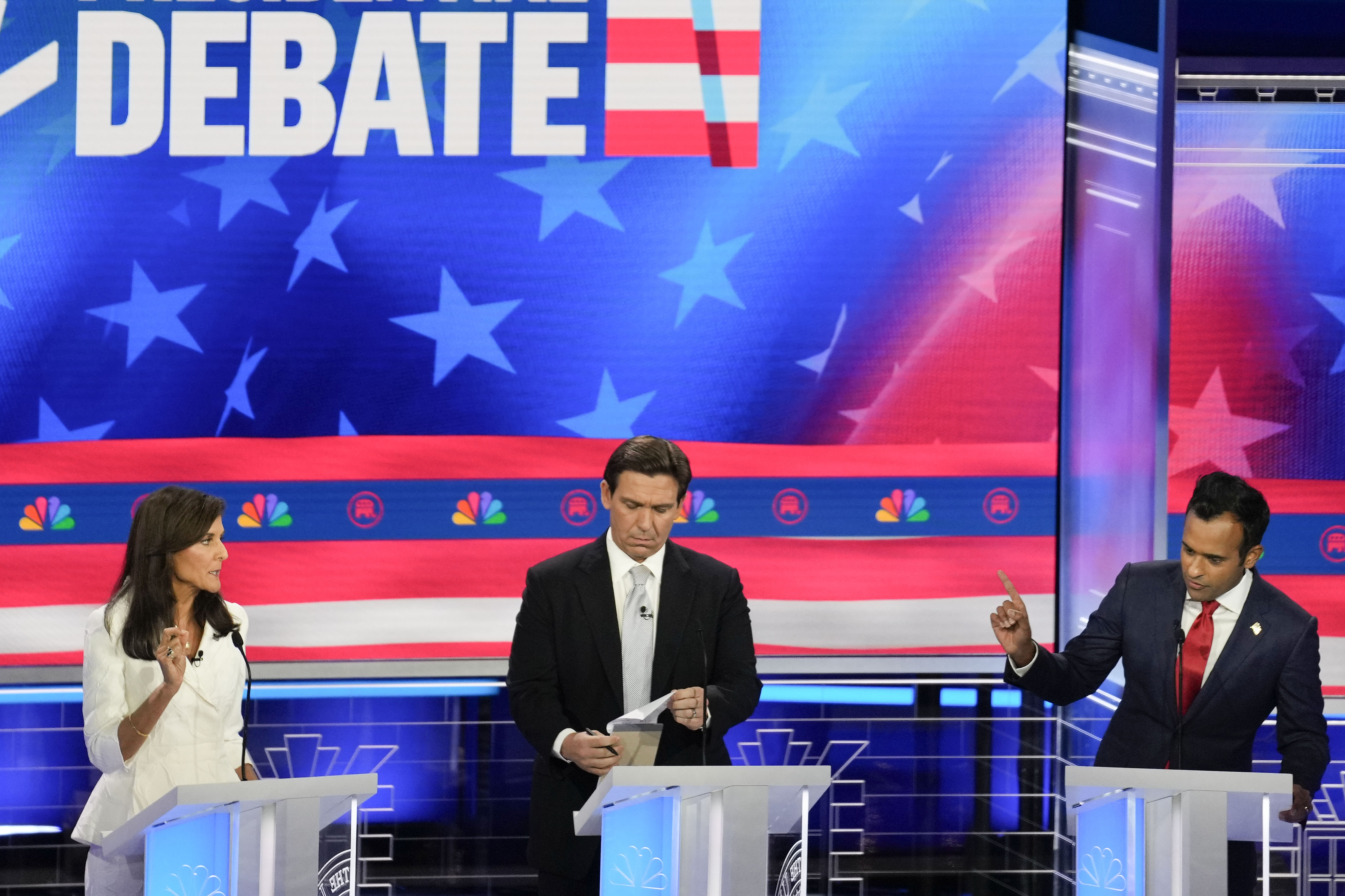 Republican presidential candidates at their podiums in front of a large blue screen that reads debate in white