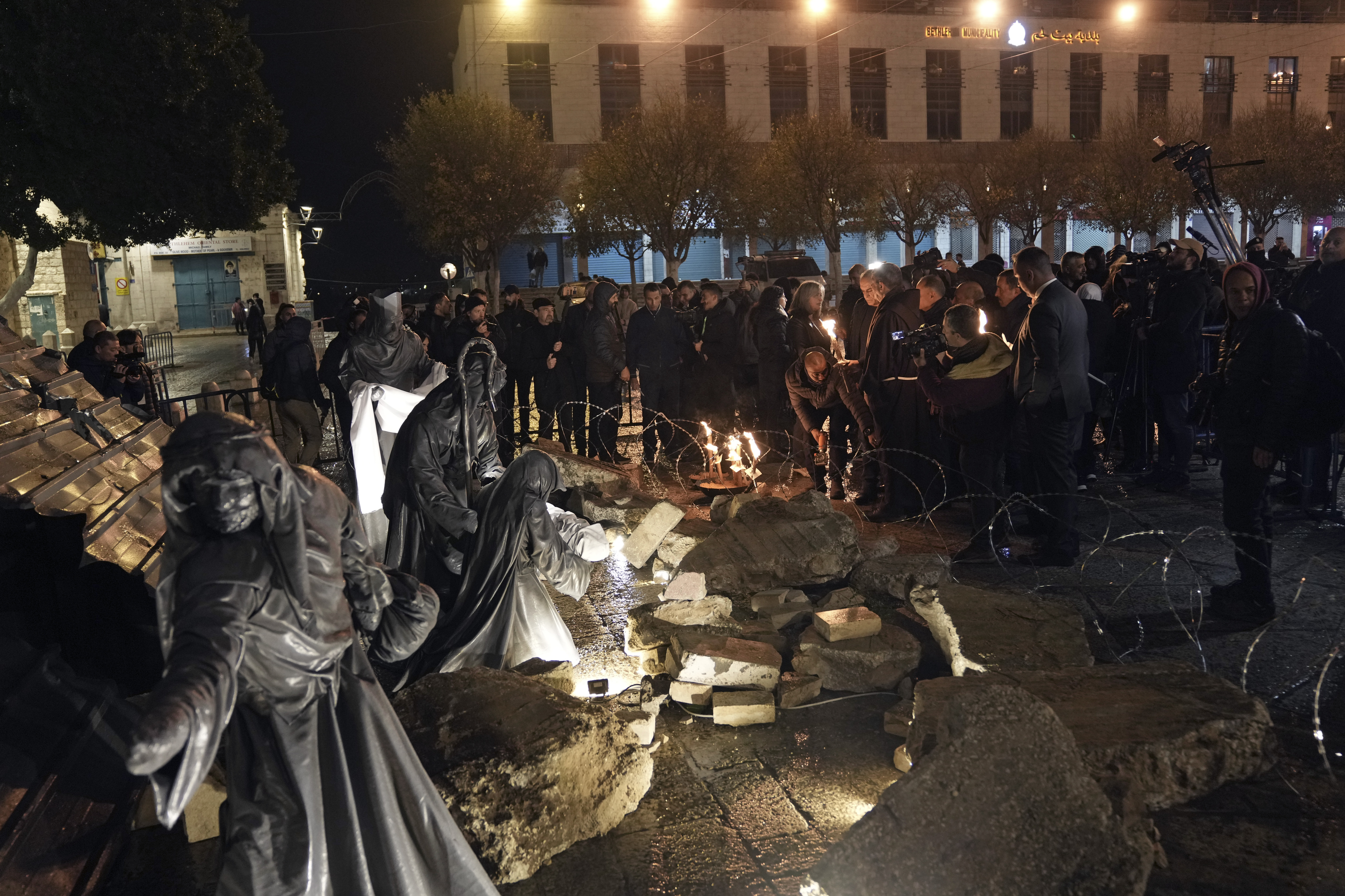 People light candles next to a nativity scene decorated to honour the victims in Gaza and asking for peace, displayed in Manger Square, adjacent to the Church of the Nativity, in the West Bank town of Bethlehem, on Friday