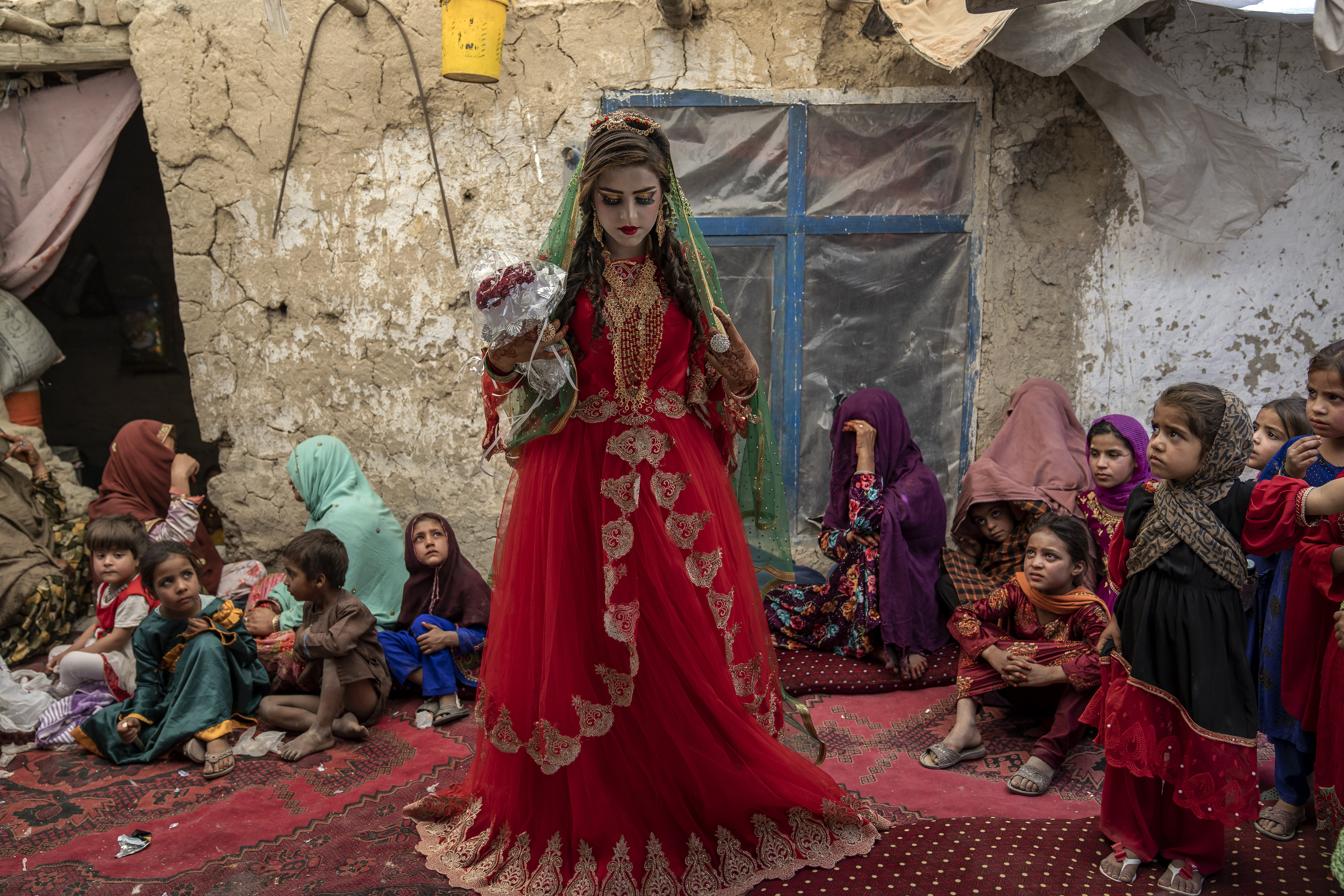 Shamila, 15, from an internally displaced family, adjusts her wedding dress in an old mud house yard, on her wedding day, on the outskirts of Kabul, Afghanistan, Friday, May 19