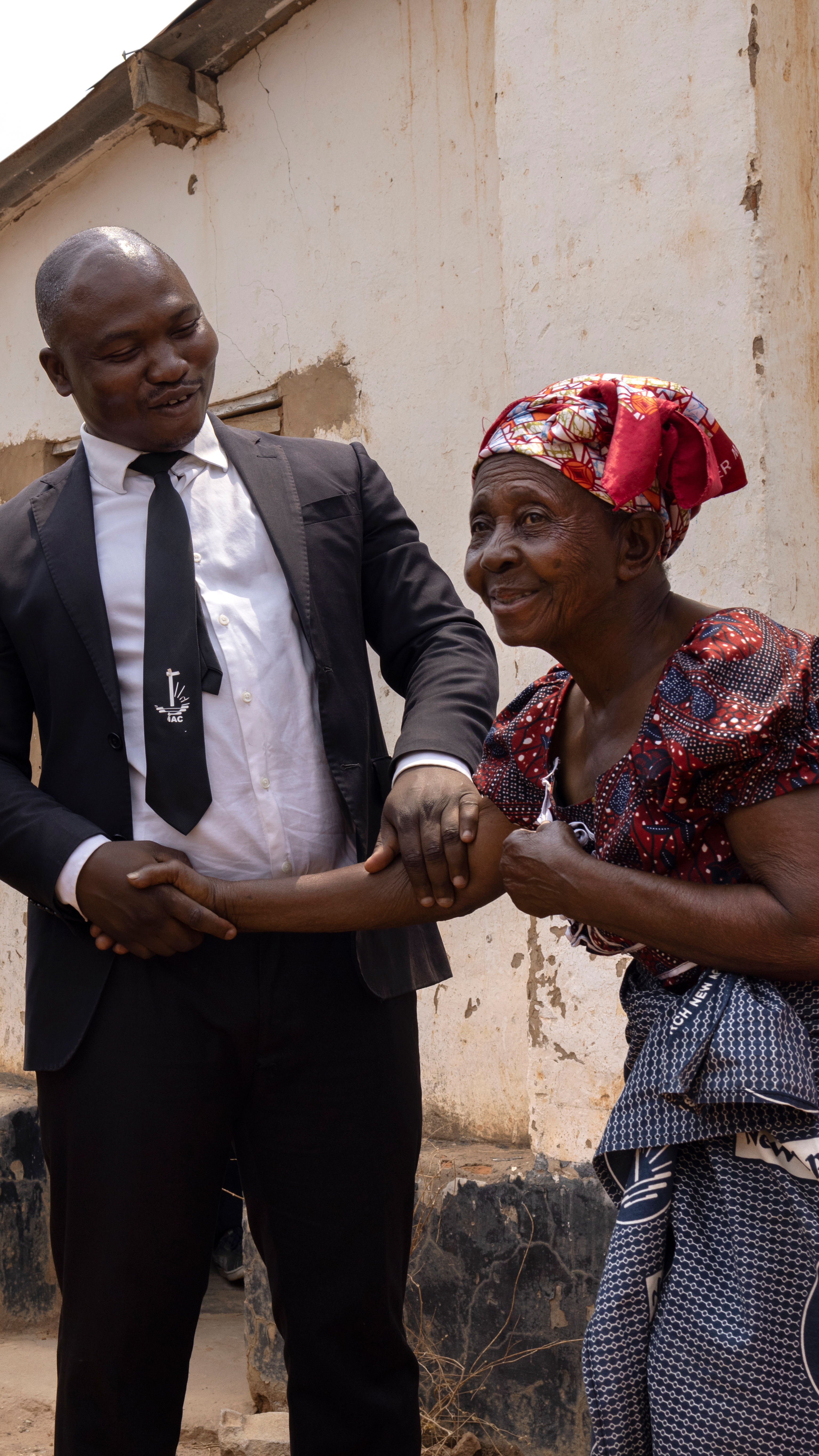 A man and woman shake hands outside a church in a refugee camp in Zambia
