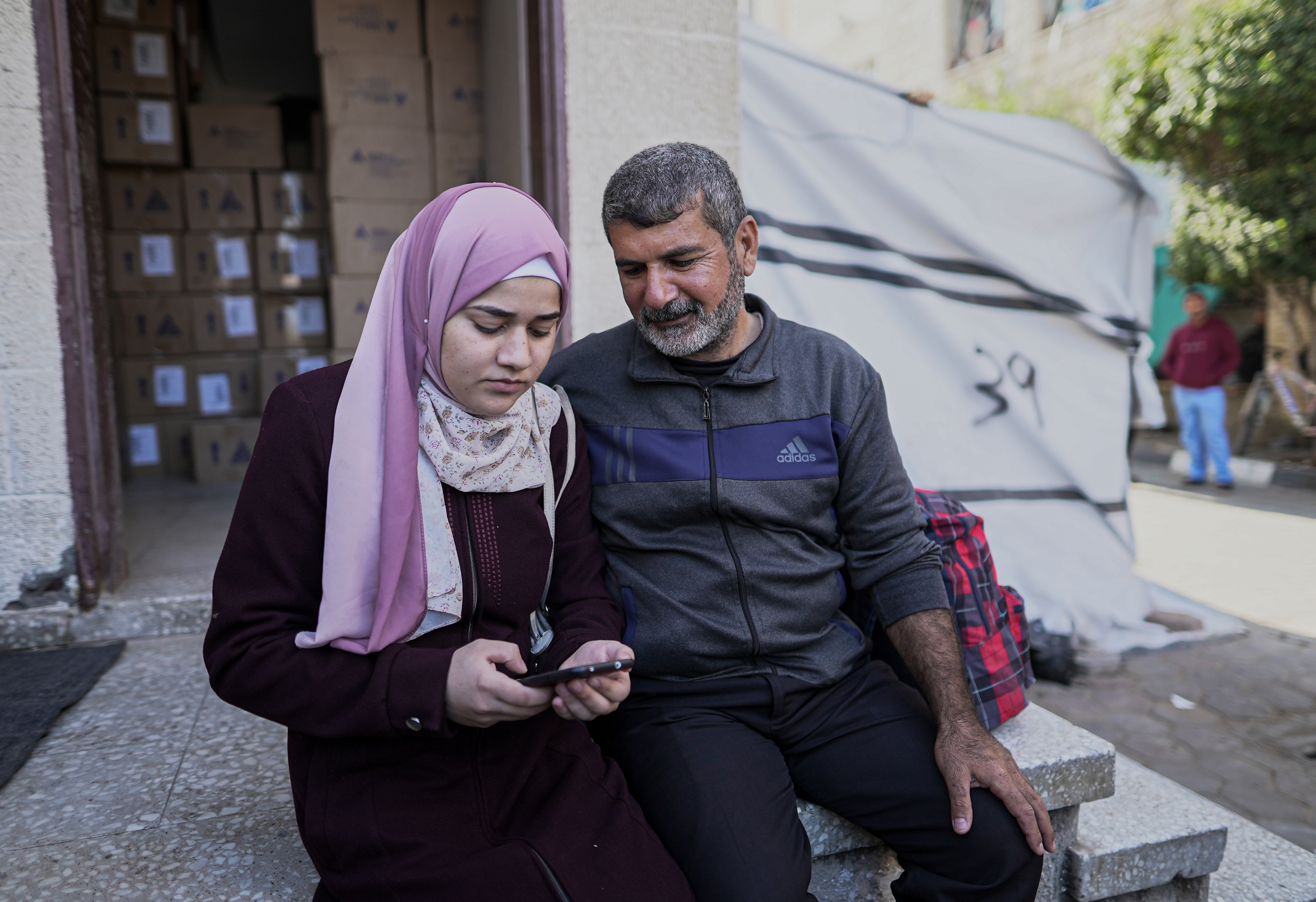 Sawsan Abu Odeh and her father Khaled sit outside Al-Aqsa Martyrs Hospital waiting for ambulance to take her to the Rafah border crossing 