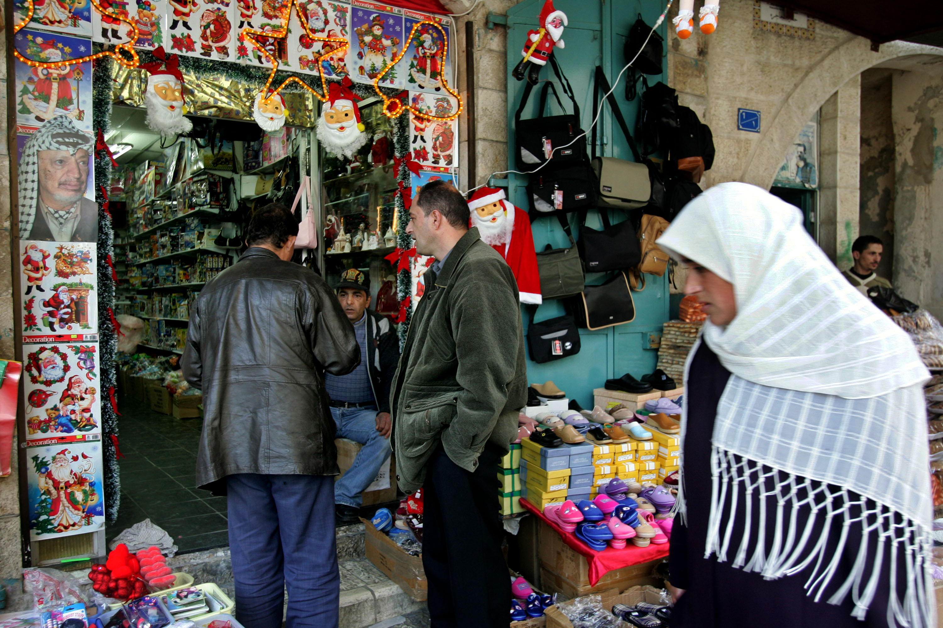 A poster of the late Palestinian leader Yasser Arafat vies for space with Christmas decorations for sale at a toy and novelty shop December 12, 2004 in the West Bank town of Bethlehem.
