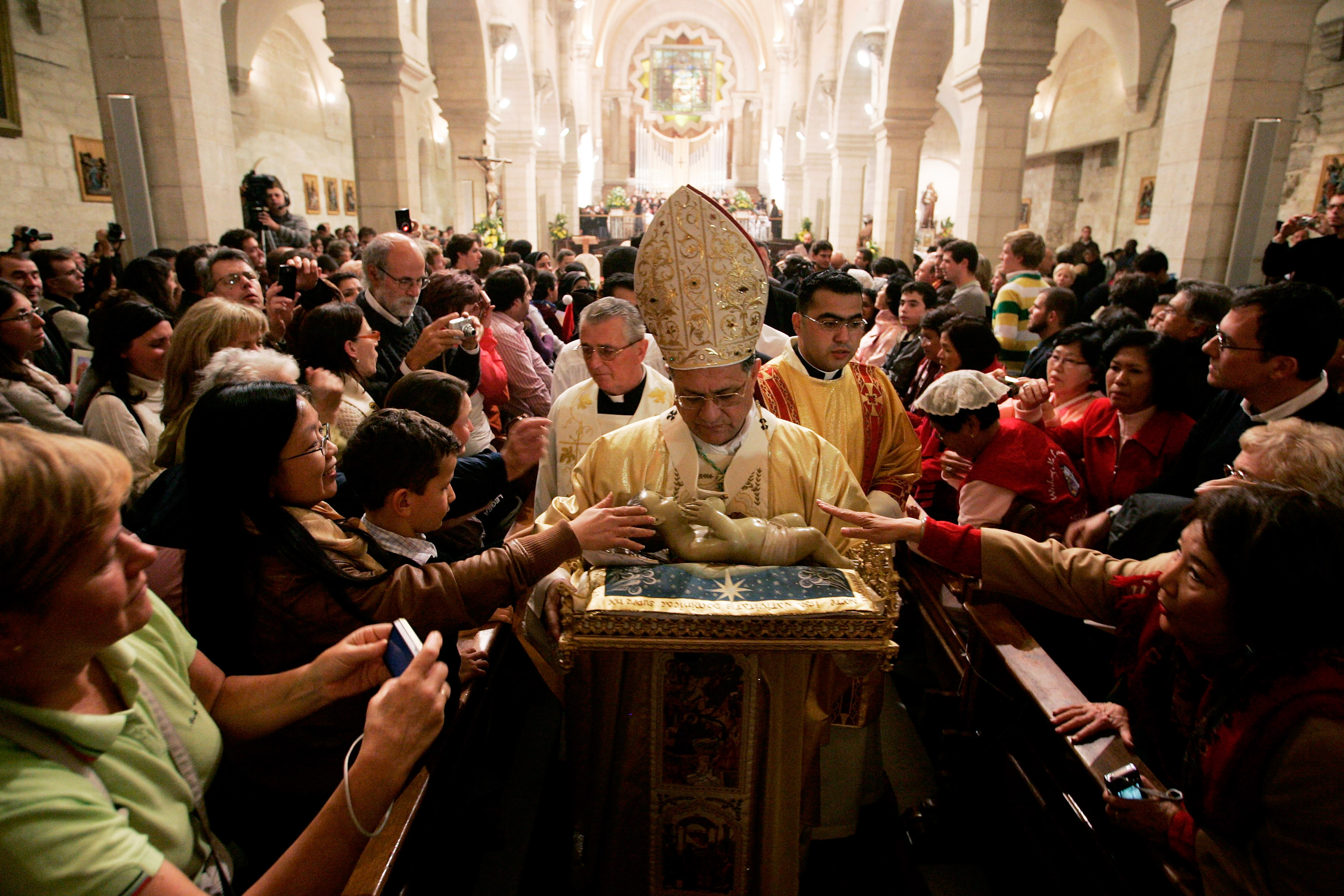 Latin Patriarch of Jerusalem Fuad Twal carries a baby Jesus following the Christmas midnight mass at the Church of the Nativity December 25, 2008 in Bethlehem, West Bank. Thousands of the faithful flocked to Bethlehem today, as the biblical birthplace of Jesus Christ hoping for a better Christmas after years of deadly violence.