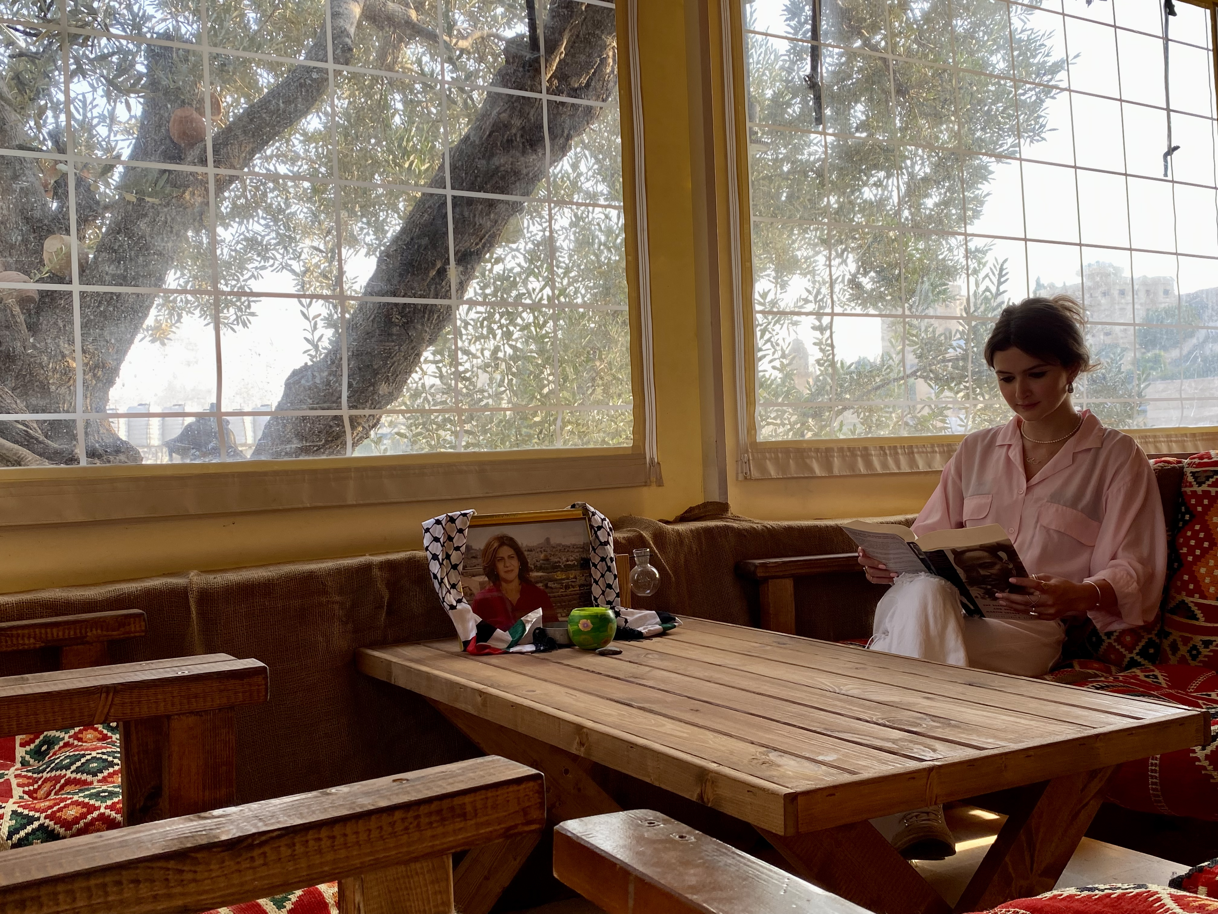 Laila Shadid in a cafe in the West Bank with a picture of Shireen Abu Akleh