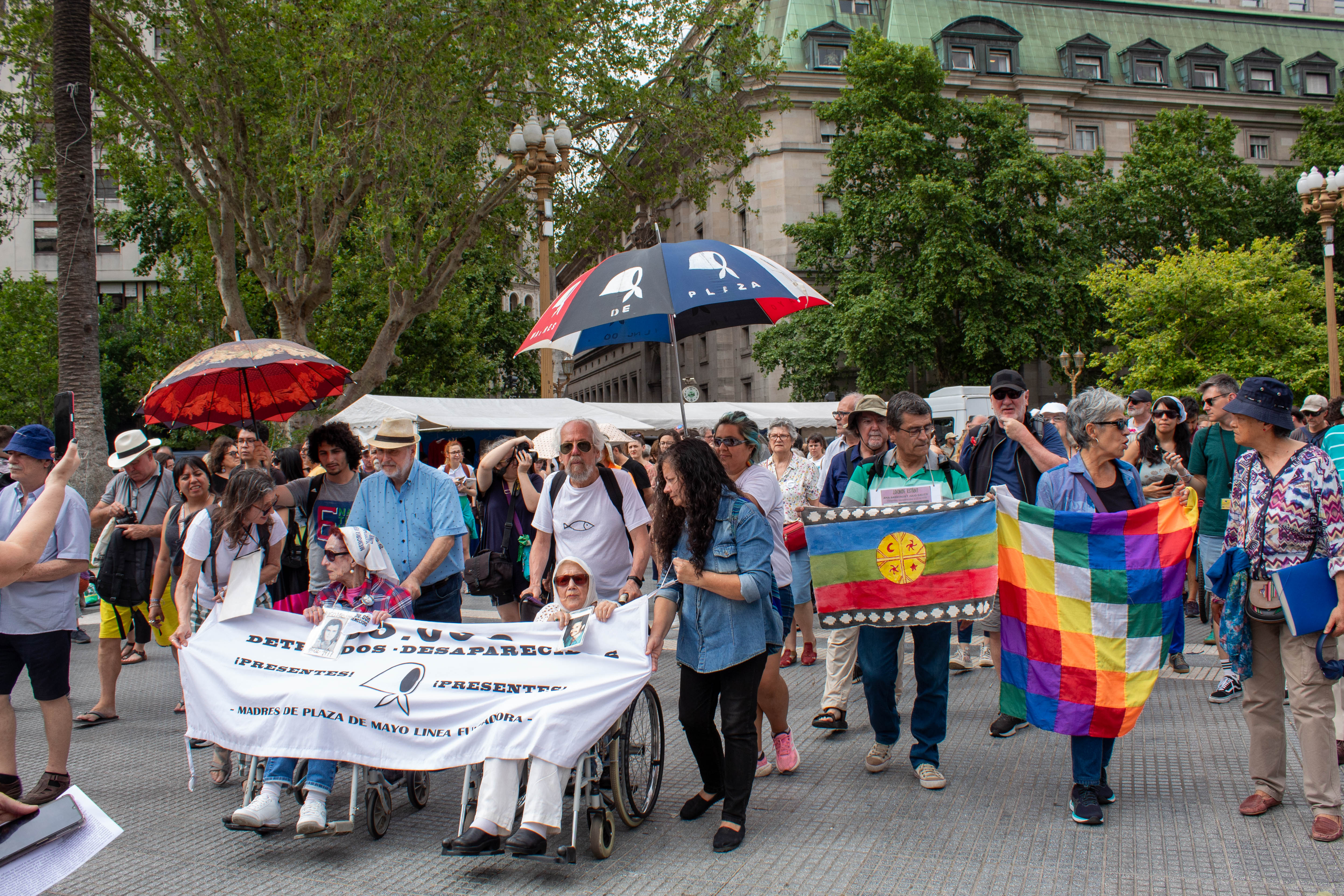Demonstrators hold up banners and umbrellas and march through the Plaza de Mayo in Buenos Aires.