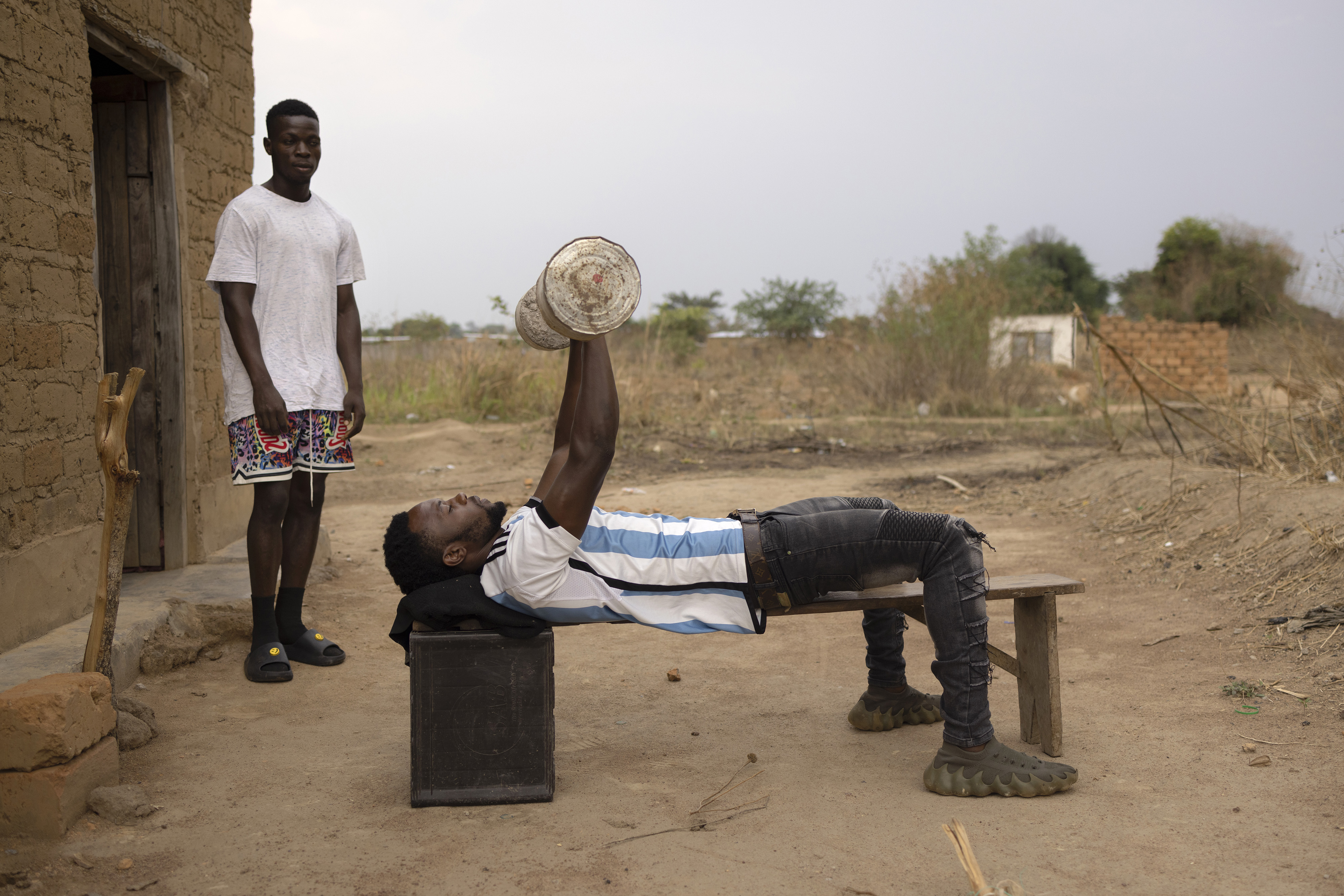 Two young men train using makeshift weights