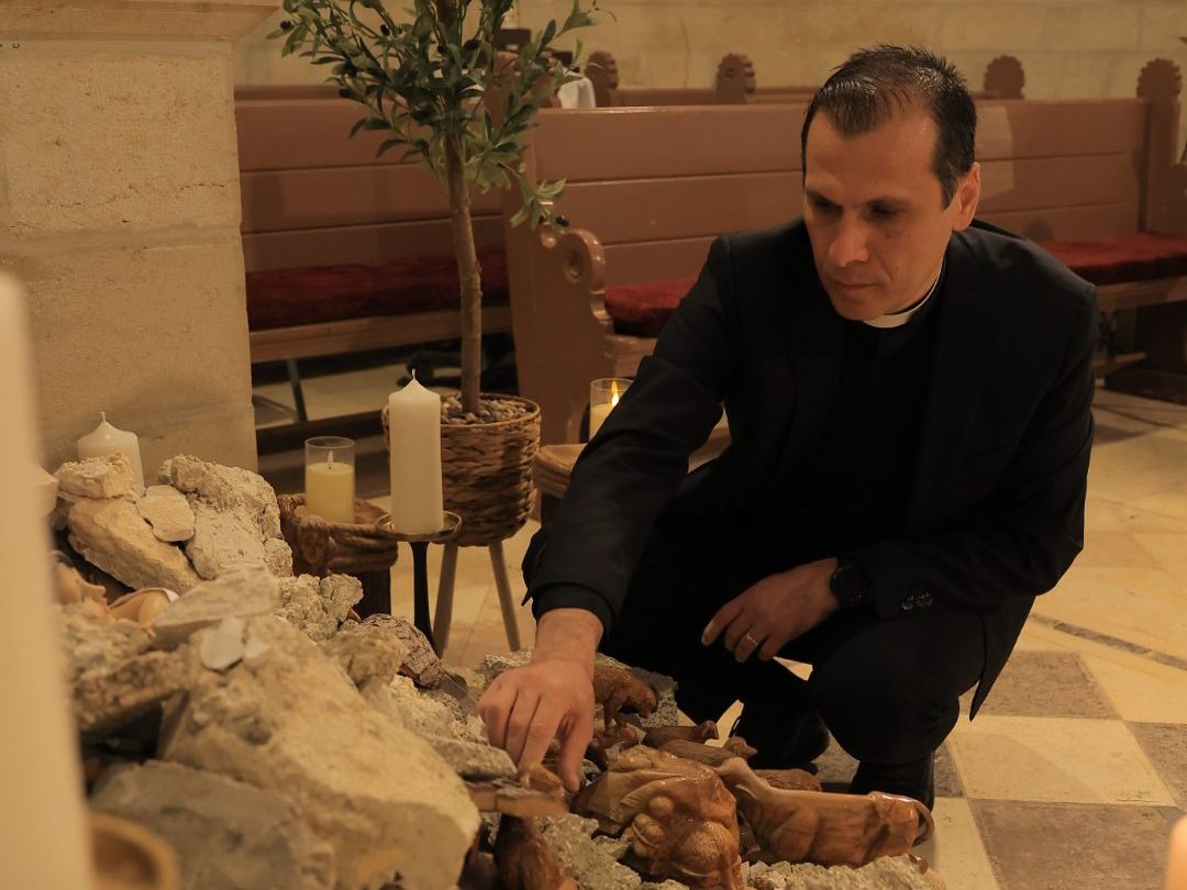 Reverend Munther Isaac kneels by the manger