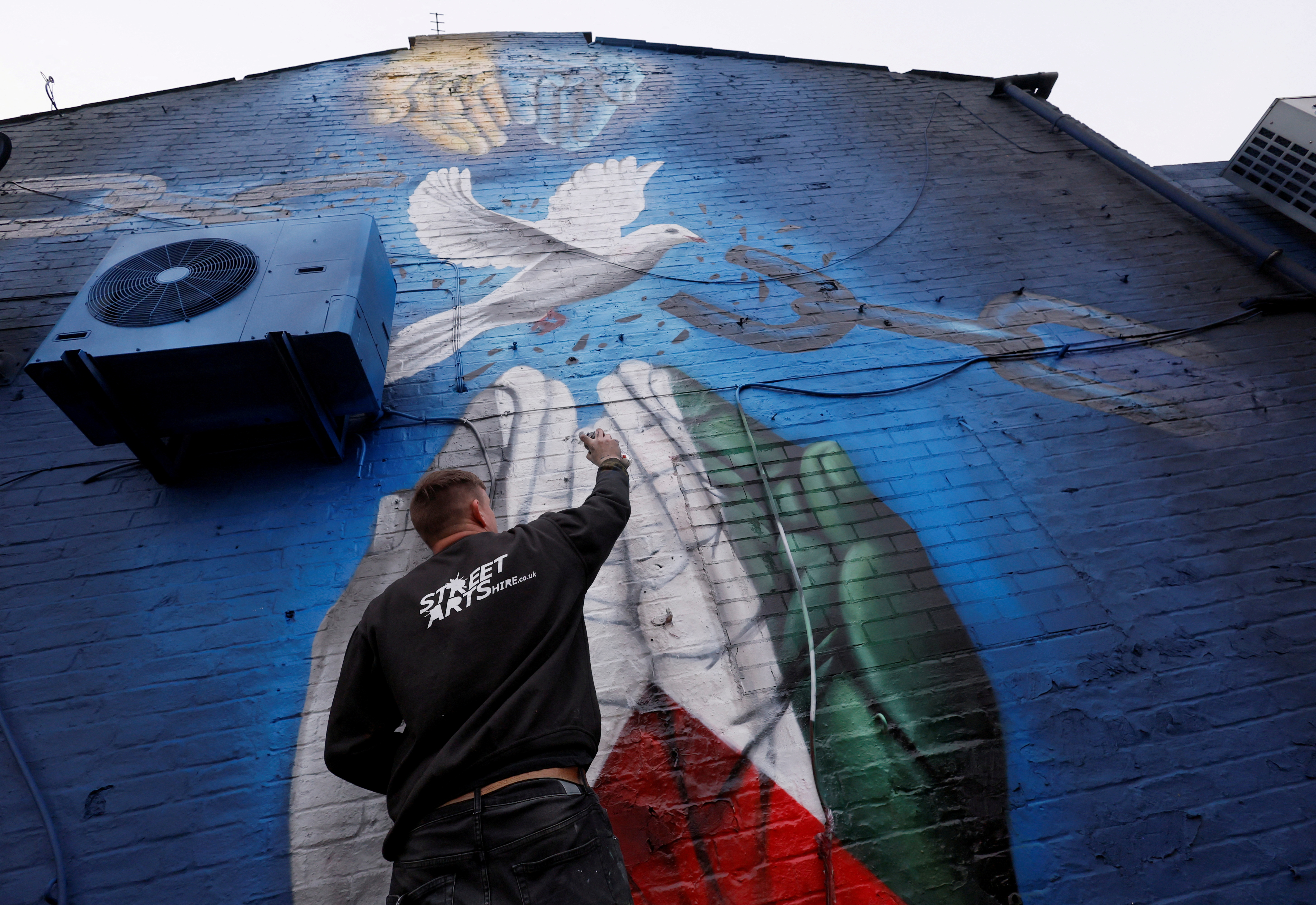 Street artist Nathan Murdoch creates an artwork in support of Ukraine and Palestine, in Peterborough, Britain, March 15, 2022. REUTERS/Andrew Couldridge TPX IMAGES OF THE DAY