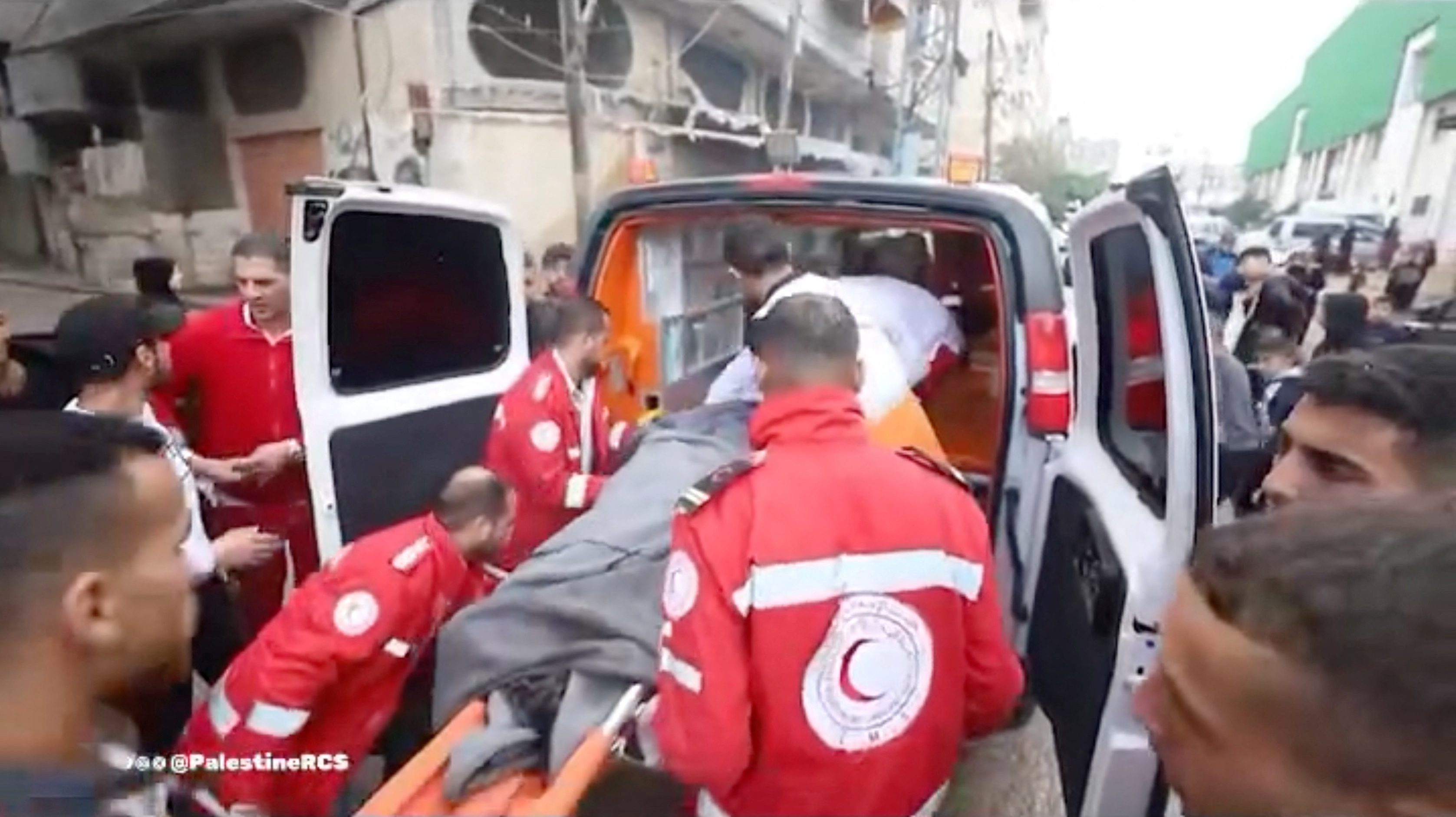Palestine Red Crescent Society (PCRS) rescuers move a casualty into an ambulance following an attack on a PCRS building,