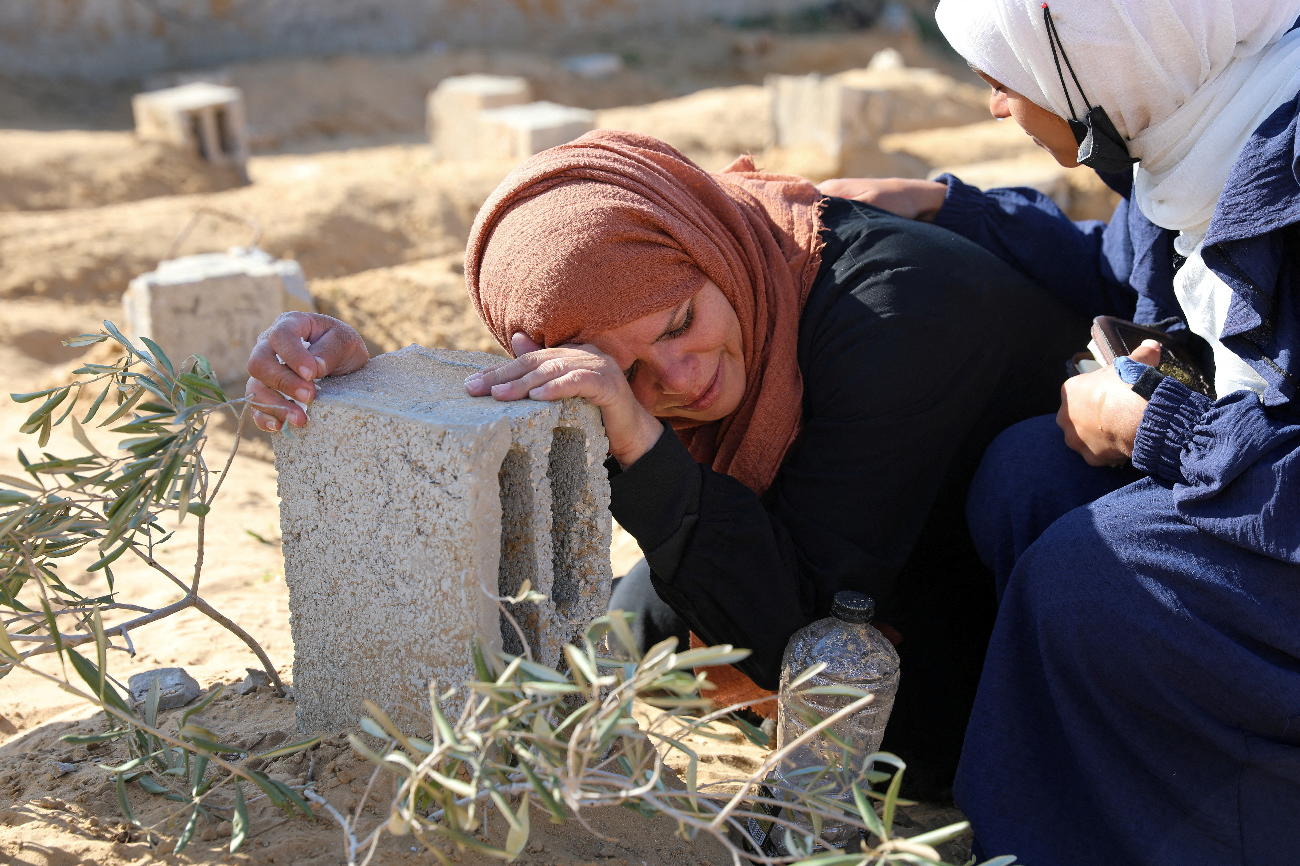 A Palestinian woman reacts at the grave of her son killed in an Israeli strike