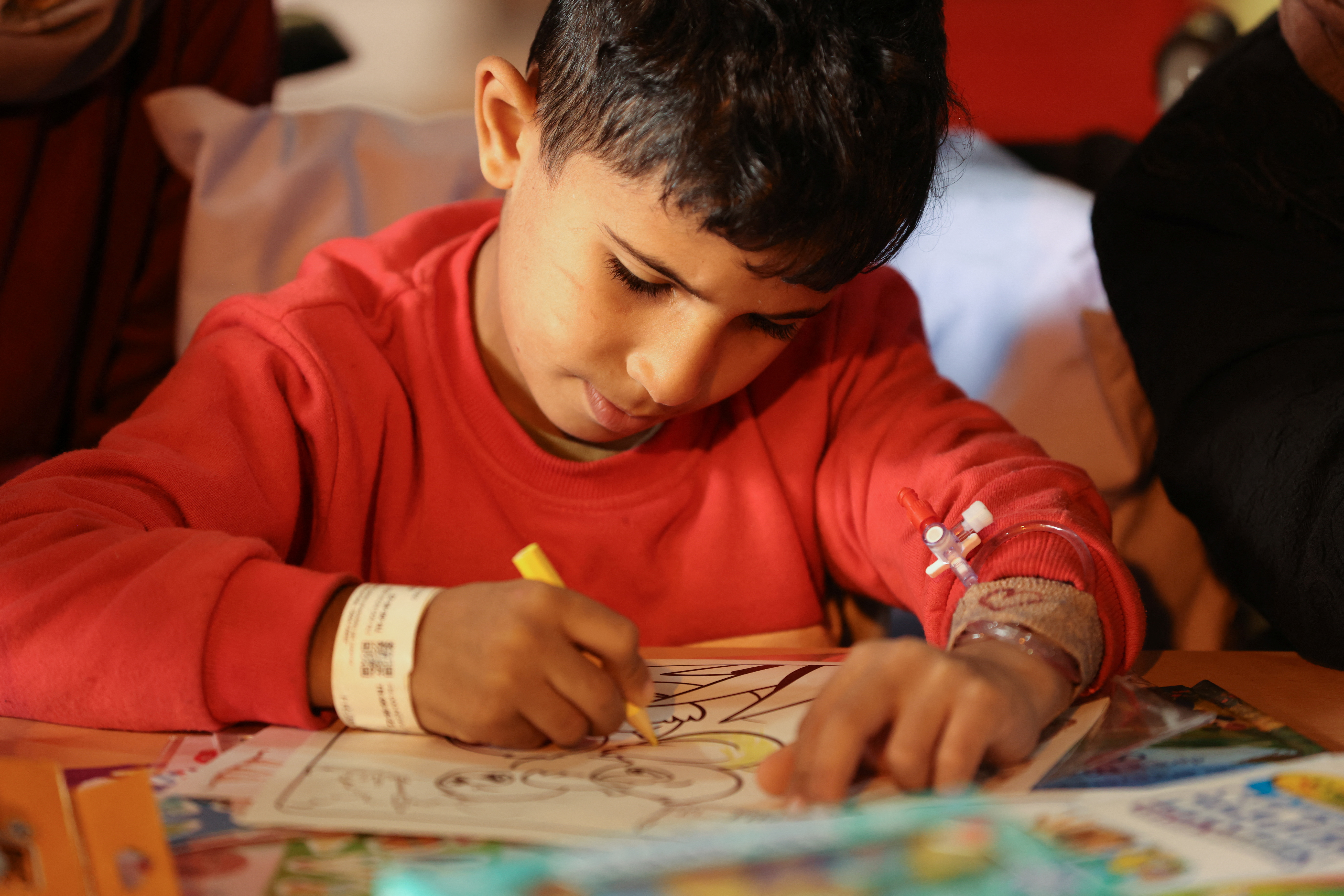 A child colours colouring pages at the hospital onboard the French ship amphibious helicopter carrier Dixmude as it docks, amid the ongoing conflict between Israel and the Palestinian Islamist group Hamas, in the city of Al-Arish, Sinai peninsula, Egypt, January 21