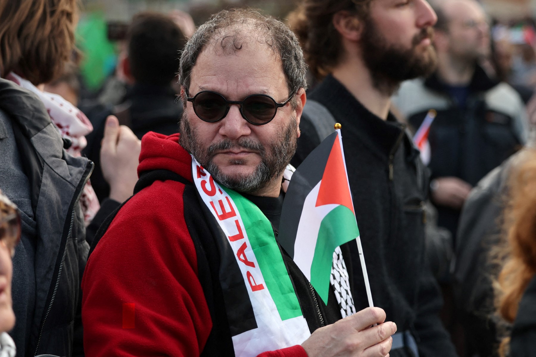 Israeli politician Ofer Cassif, centre, holds a Palestinian flag