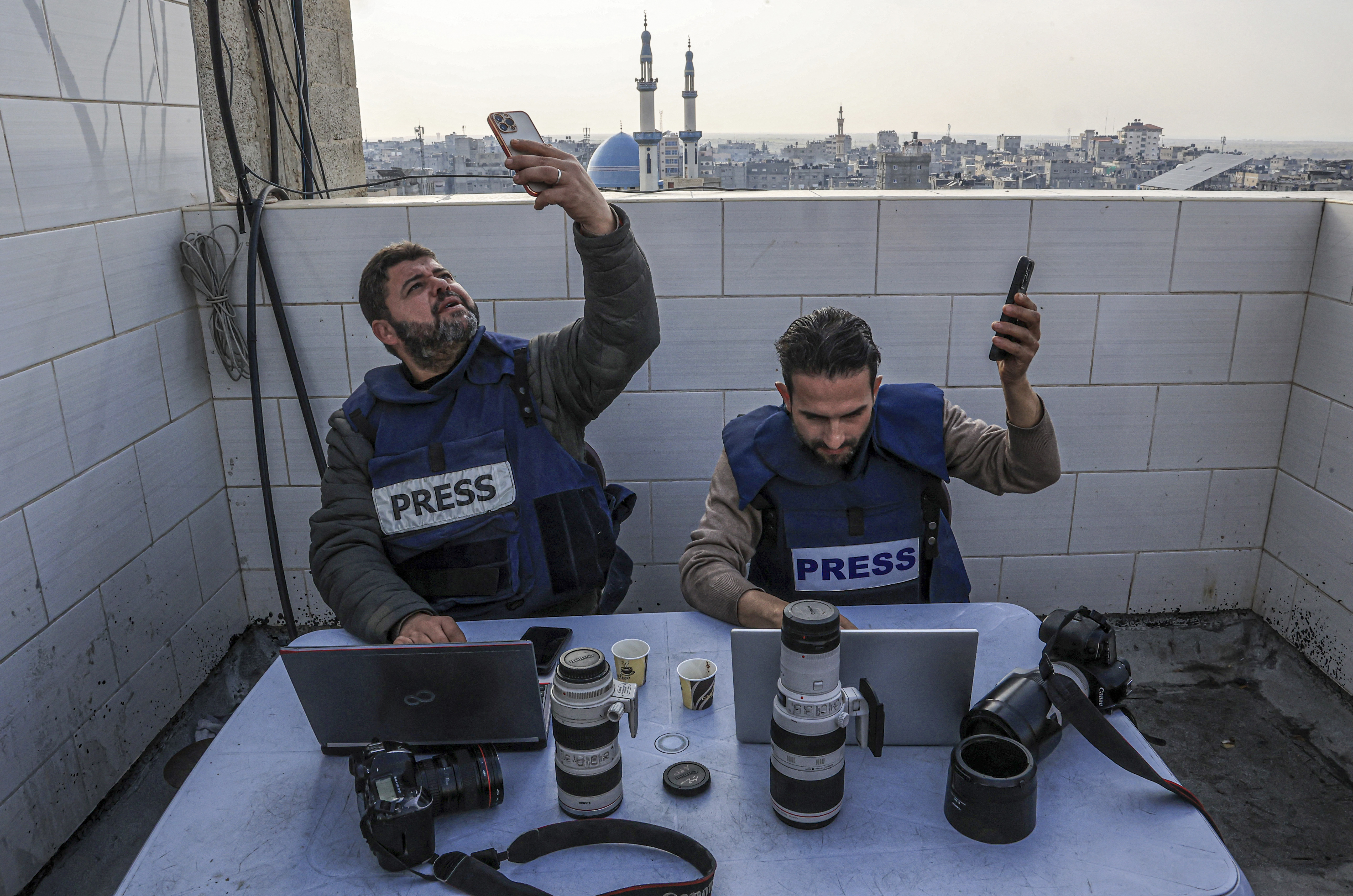 Palestinian journalists attempt to connect to the internet using their phones in Rafah on the southern Gaza Strip on December 27