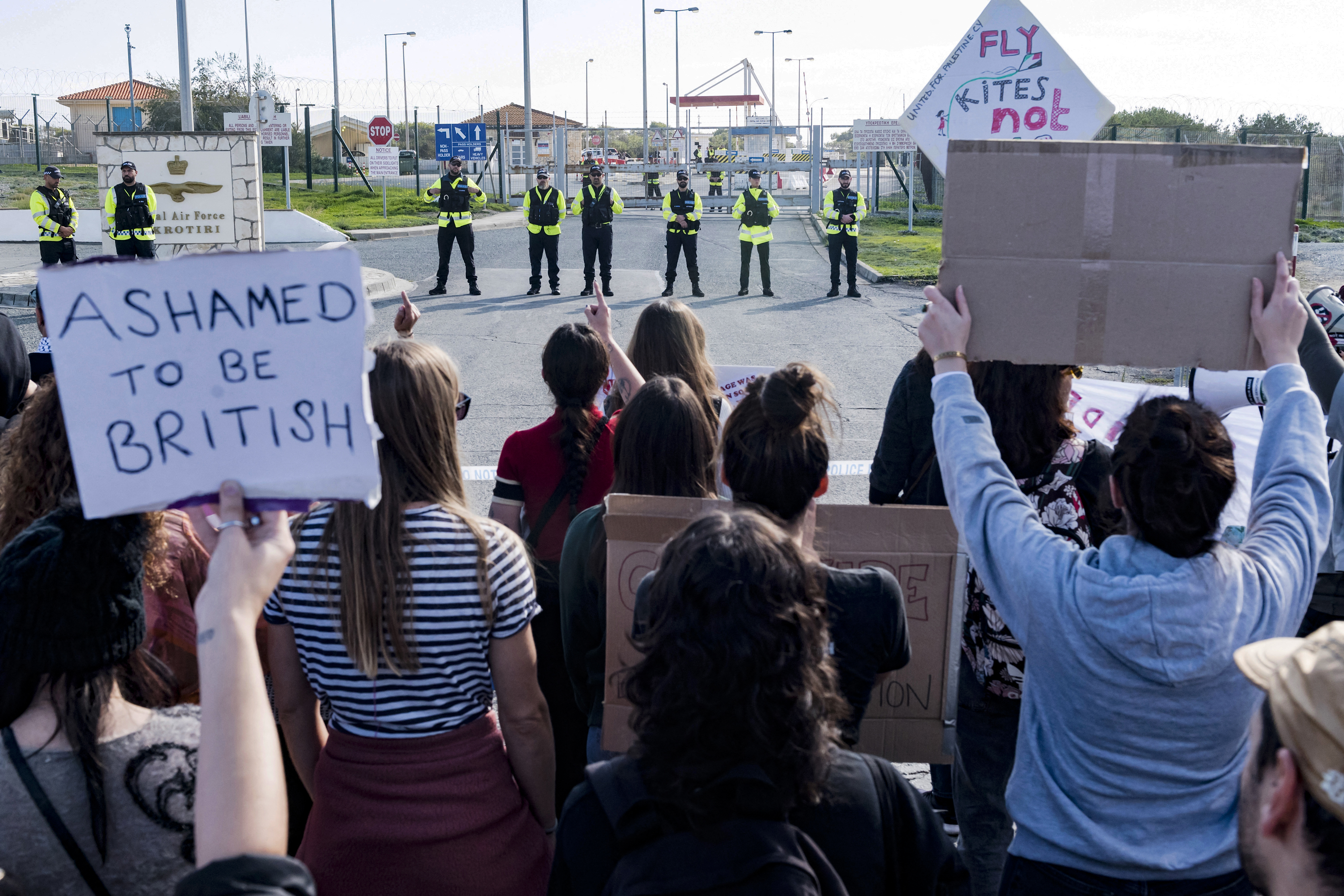 people hold protest signs in front of police in yellow vests