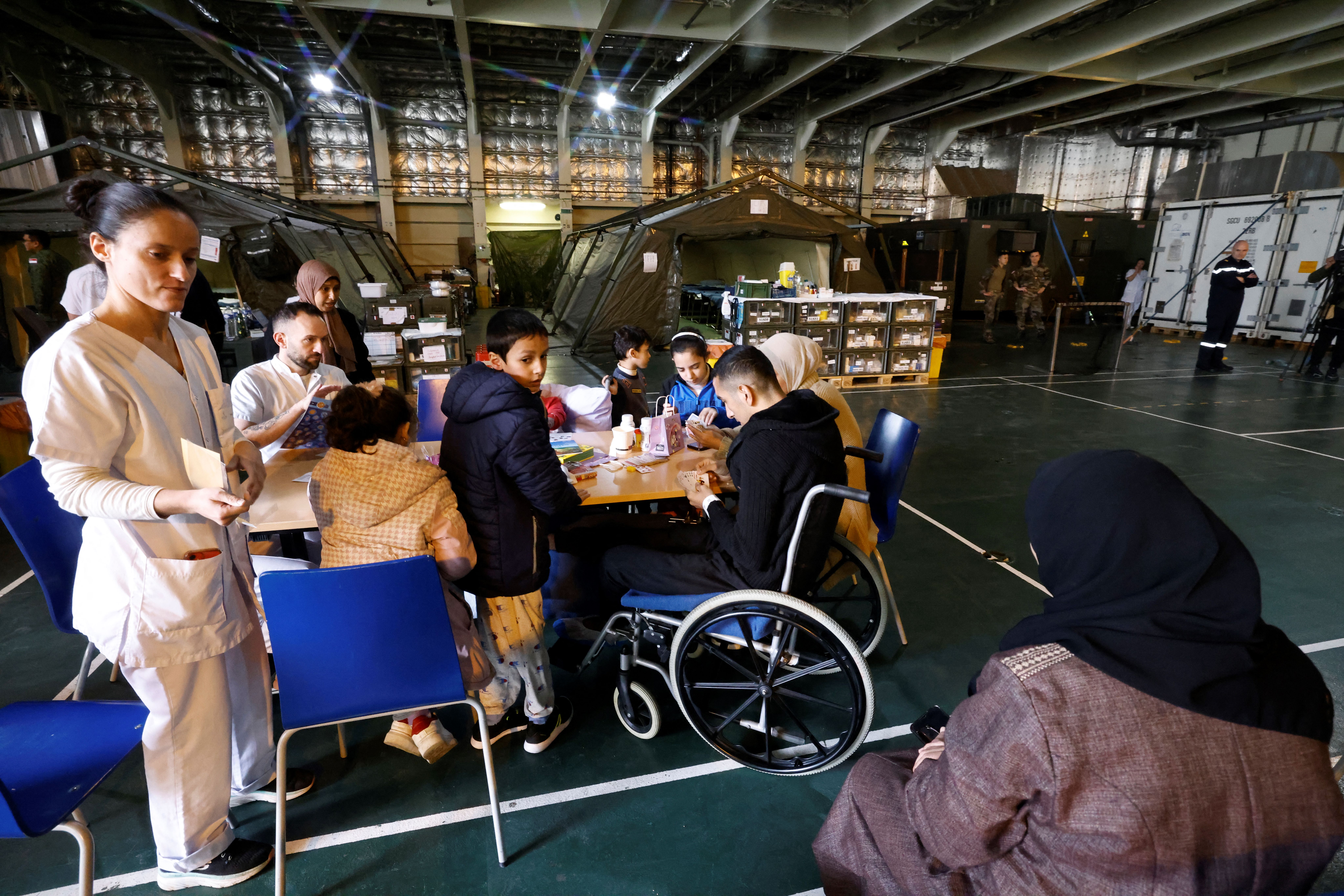 Military medical personnel and Palestinian youth and children are seated onboard the French LHD Dixmude military ship, which serves as a hospital to treat wounded Palestinians, as it docks at the Egyptian port of Al-Arish on January 21