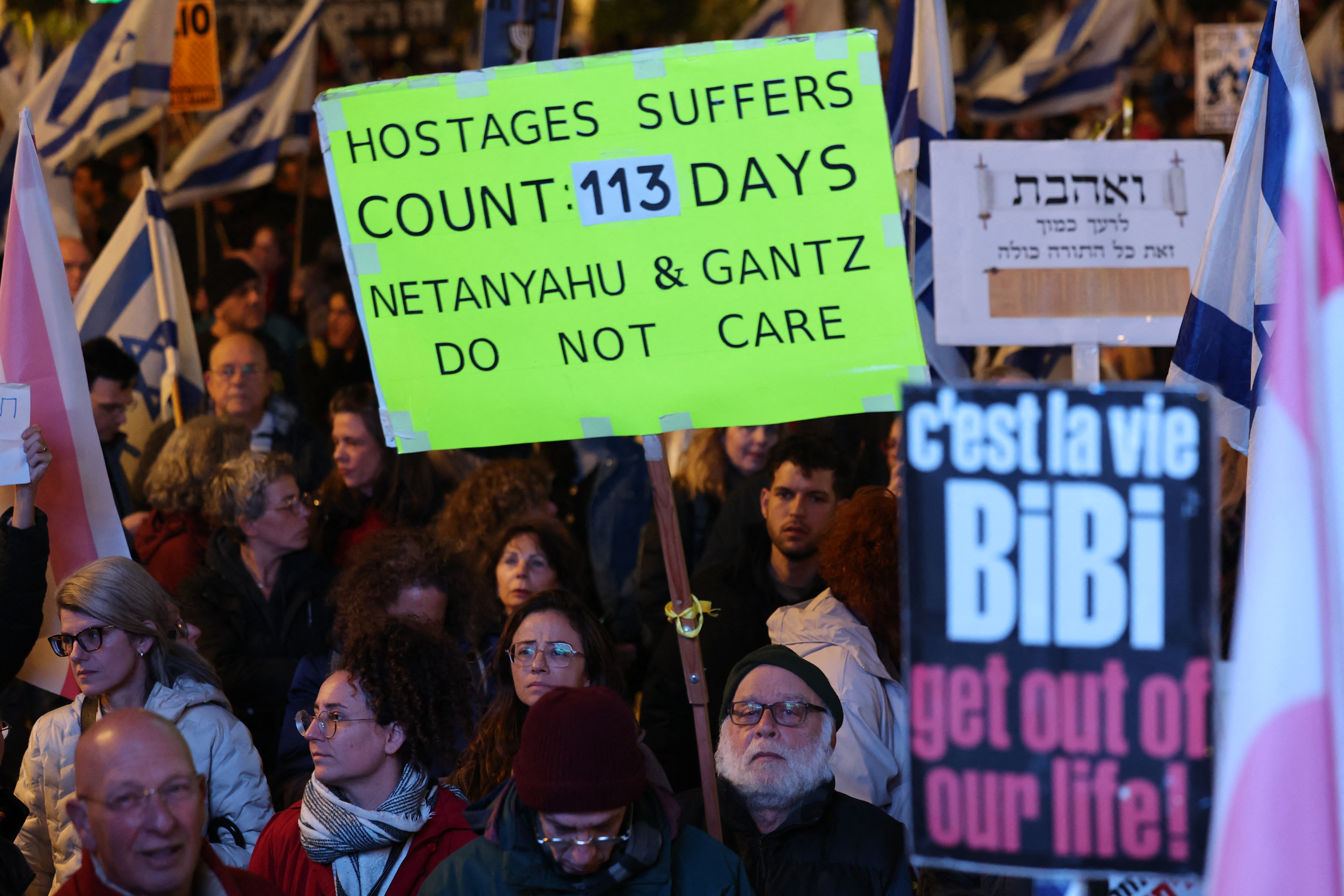 Protesters lift national flags and placards during a rally in Israel's central city of Tel Aviv on January 27
