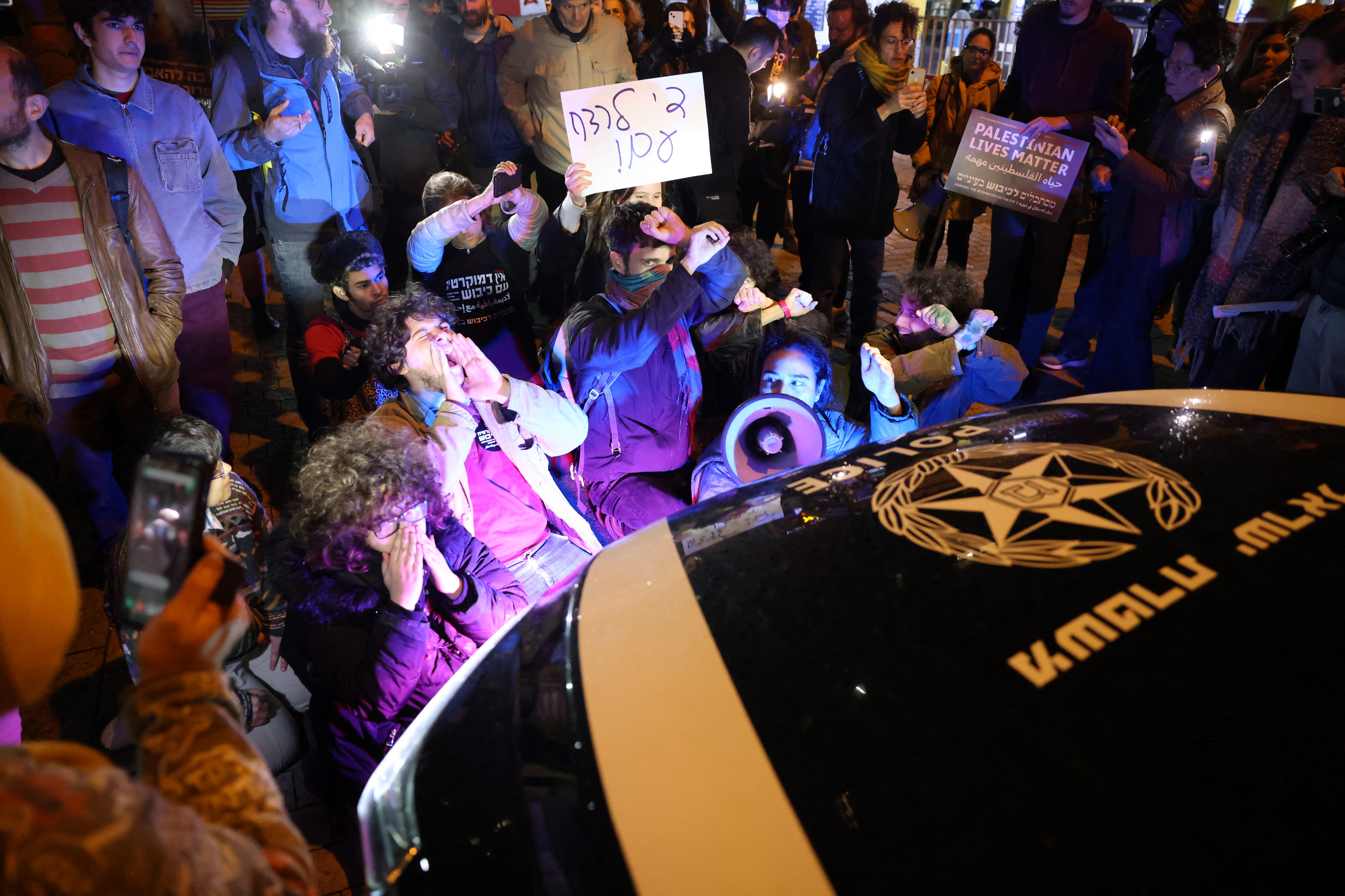Israeli left-wing activists block a police car, to protest after a fellow protester was arrested, on the sidelines of a demonstration against the war in Gaza