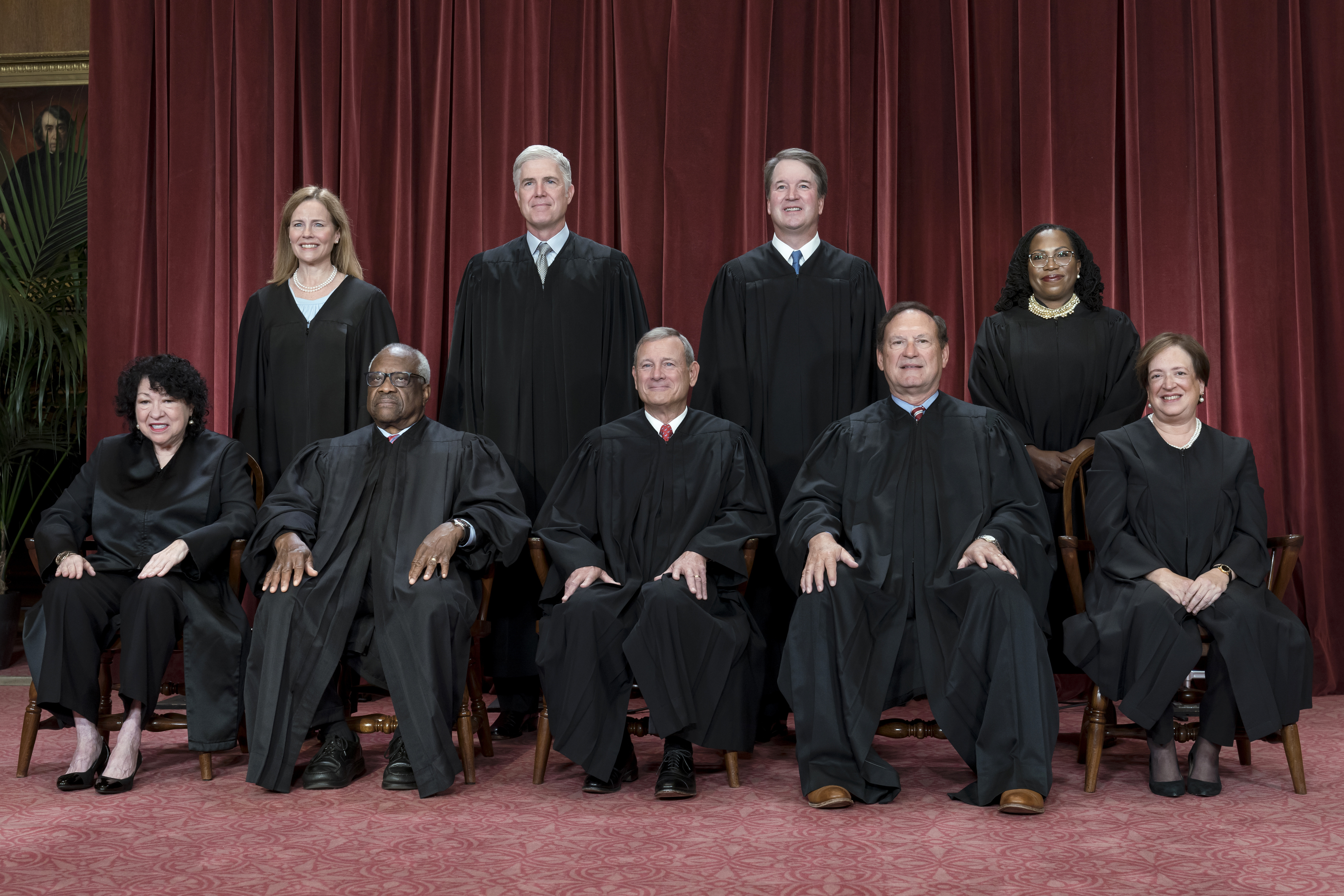 A portrait photo of all nine US Supreme Court justices, dressed in black robes and arranged in two lines, some seated, some standing.