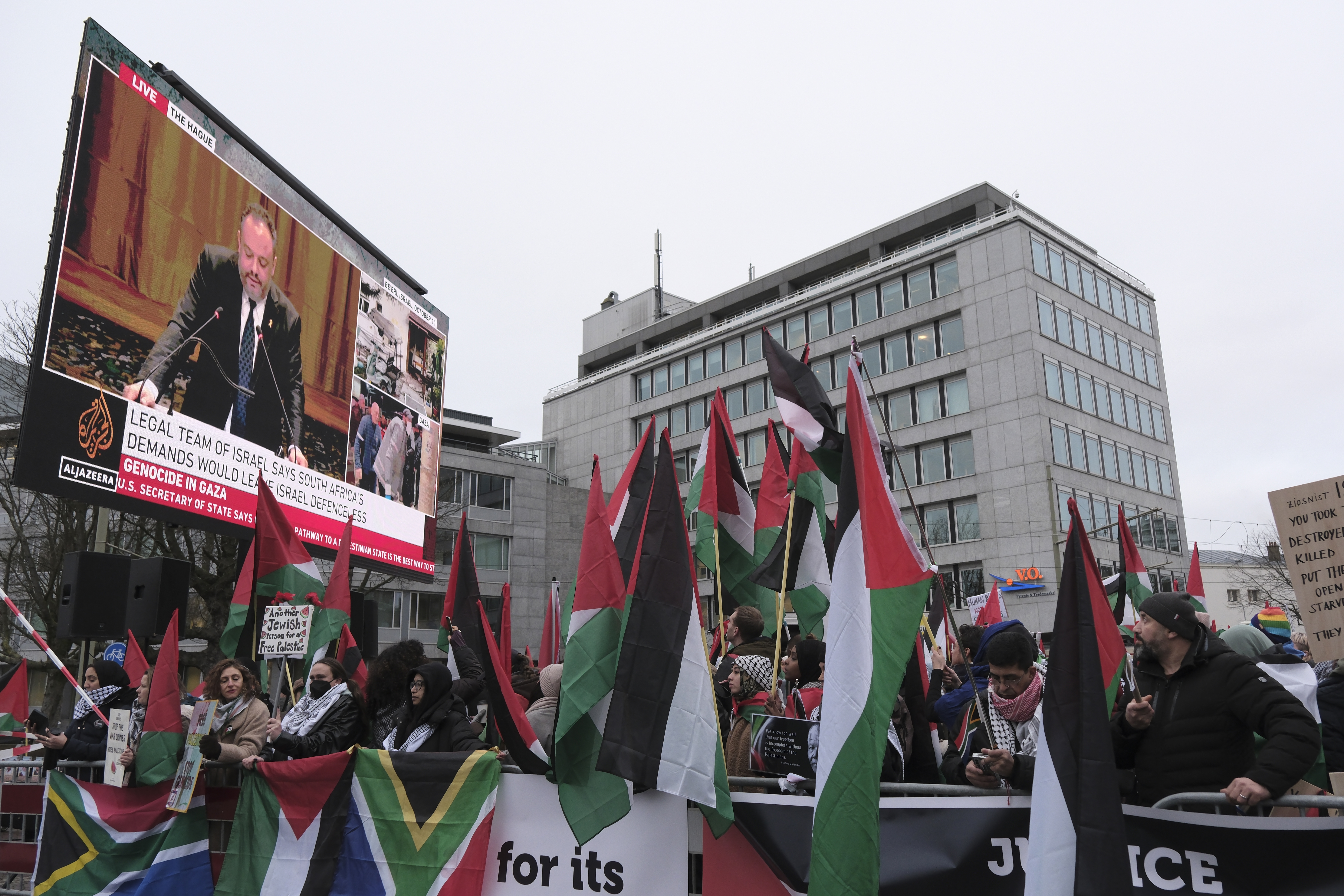 Protesters carry flags and banners outside the International Court of Justice in The Hague, Netherlands, Friday, Jan. 12, 2024. The United Nations' top court opened hearings Thursday into South Africa's allegation that Israel's war with Hamas amounts to genocide against Palestinians, a claim that Israel strongly denies. (AP Photo/Patrick Post)