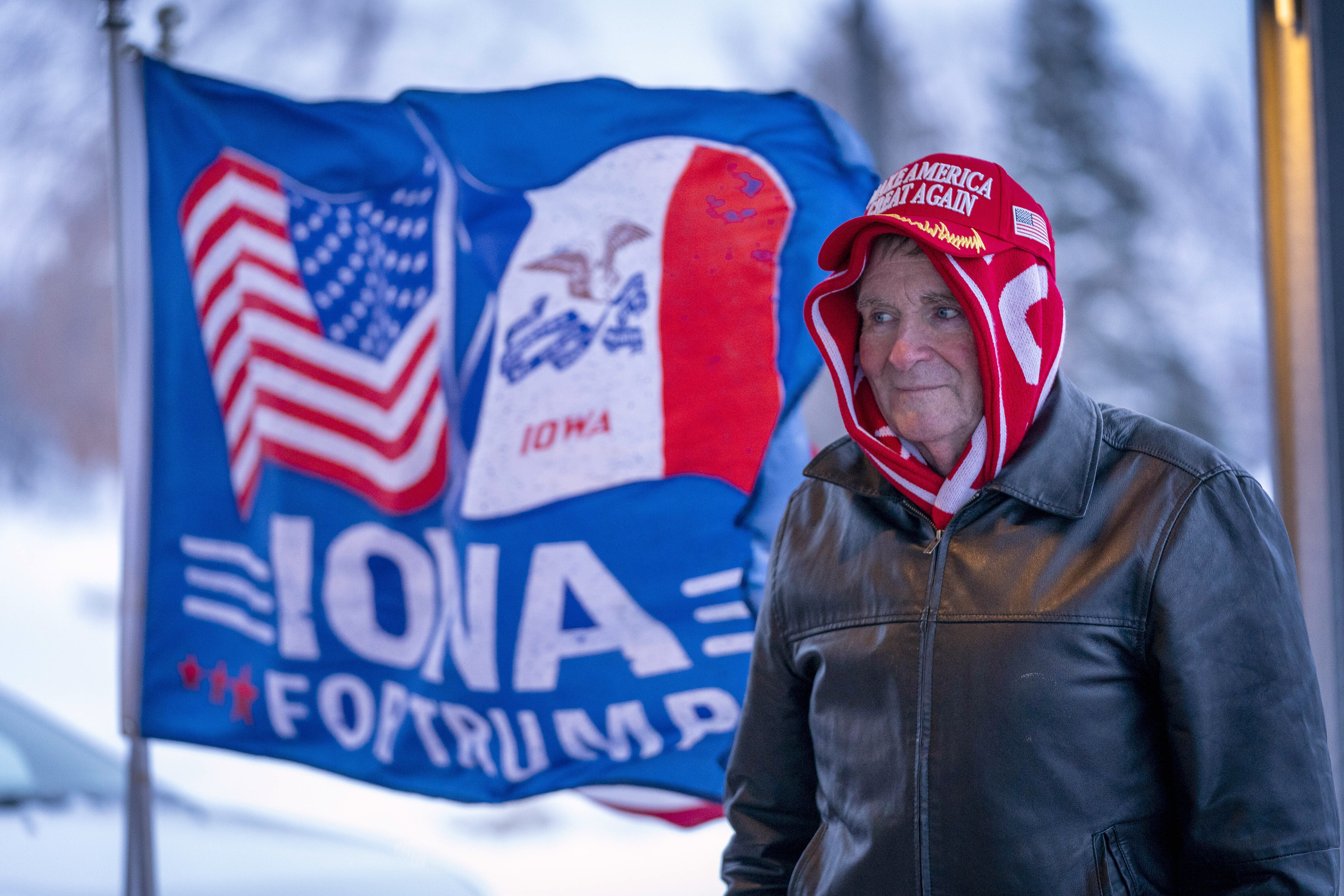 A man stands next to a flag that reads "Iowa for Trump" outside the the Machine Shed in Urbandale, Iowa, Jan. 11, 2024.