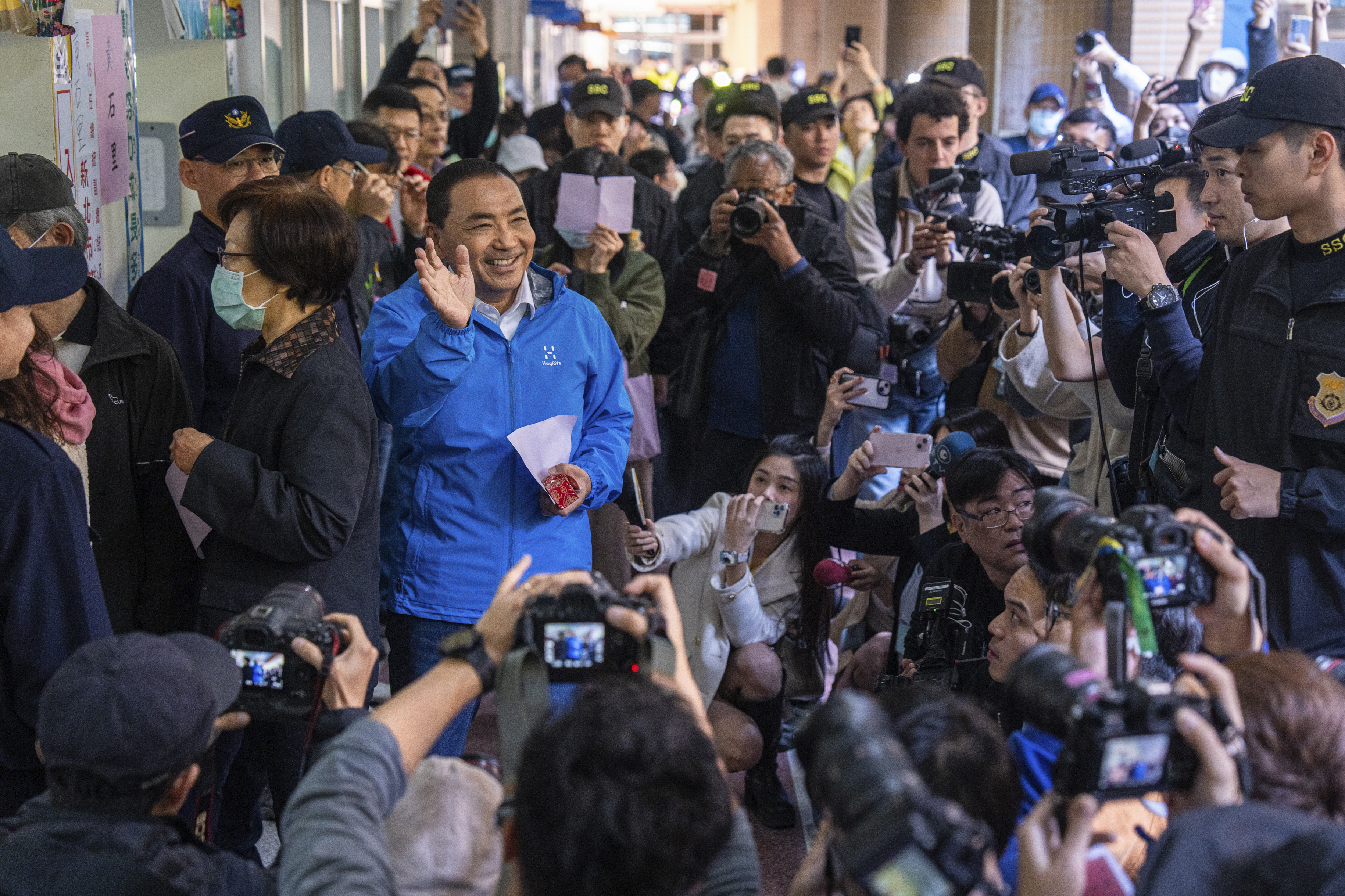 Kuomintang (KMT) presidential candidate Hou Yu-ih, center left, waves on his arrival at a polling station in New Taipei City, Taiwan, Saturday, Jan. 13,
