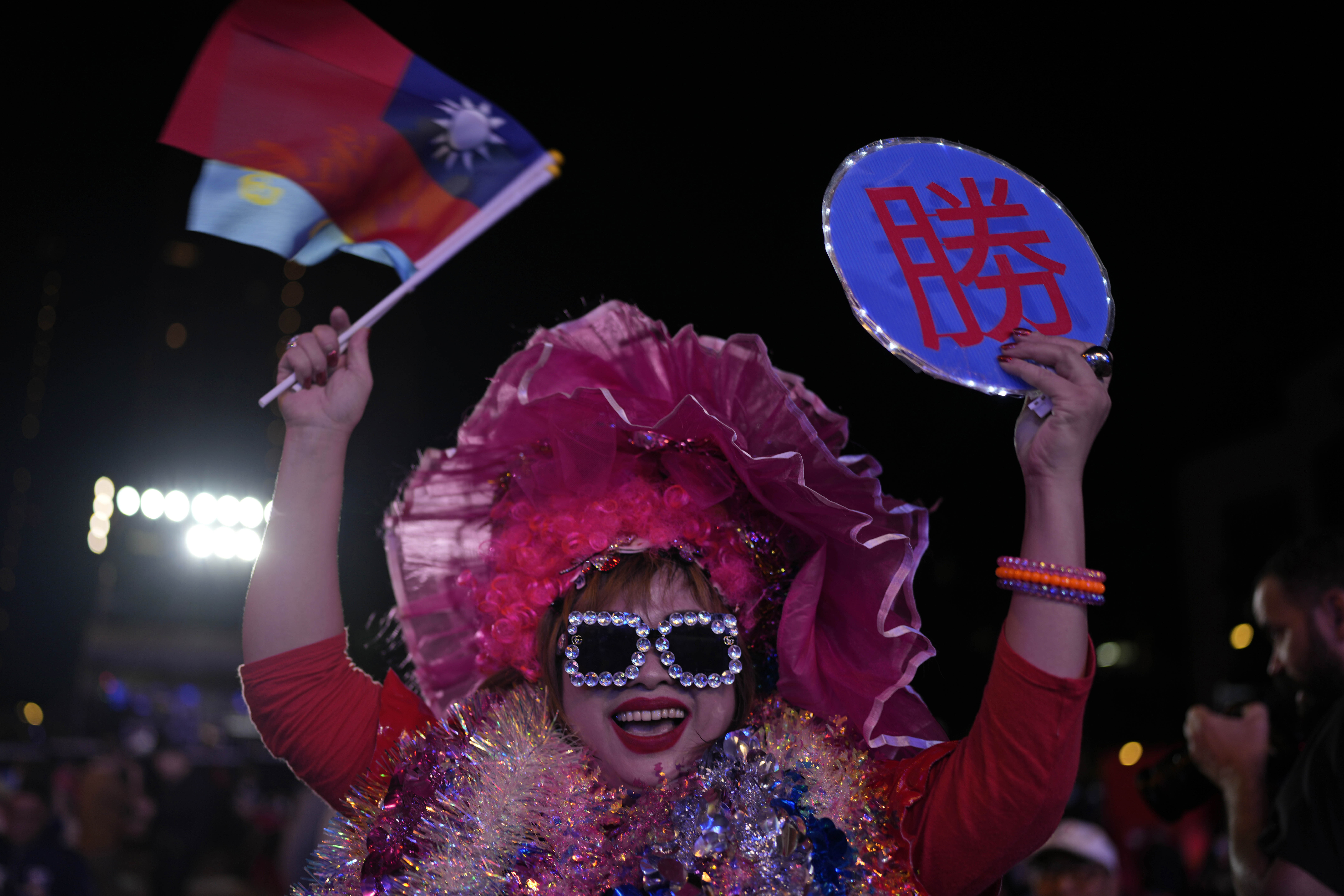 A Kuomintang (KMT) party supporters waves her national flag as votes are counted in New Taipei City, Taiwan, Saturday, Jan. 13