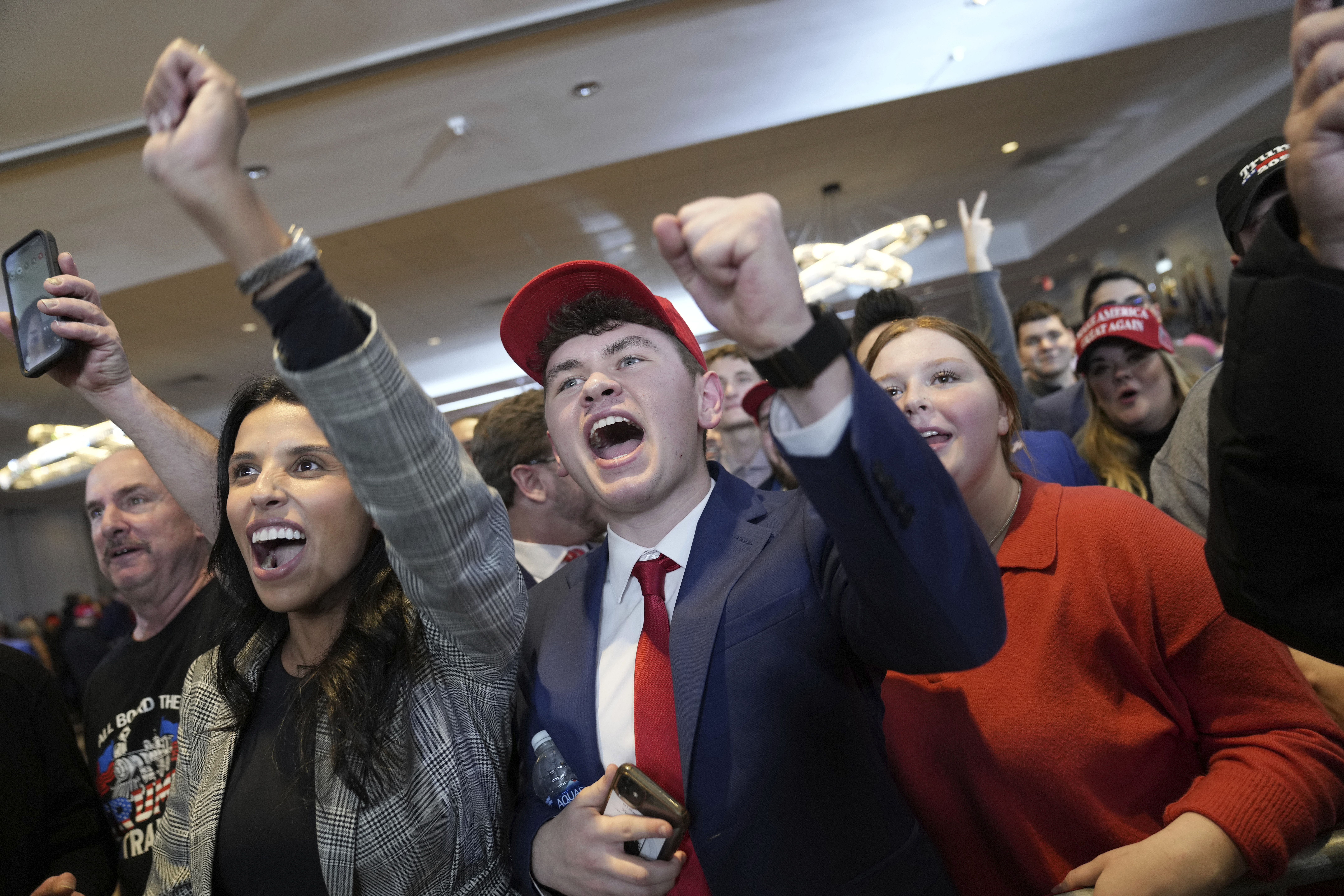 Trump supporters raise fists and yell triumphantly at campaign headquarters.