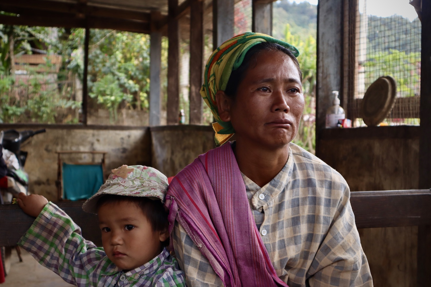 Khin Lone with her youngest child. They are seated inside.