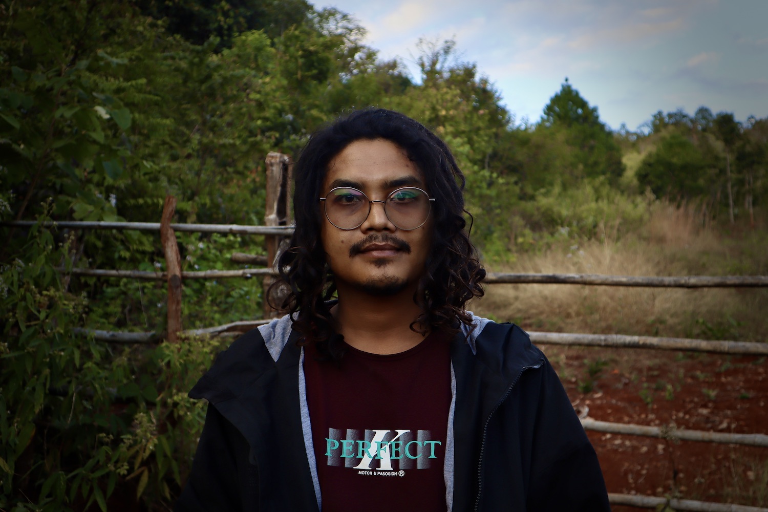 Dr Oak, He is standing outside. He is wearing glasses and has long hair and a moustache.