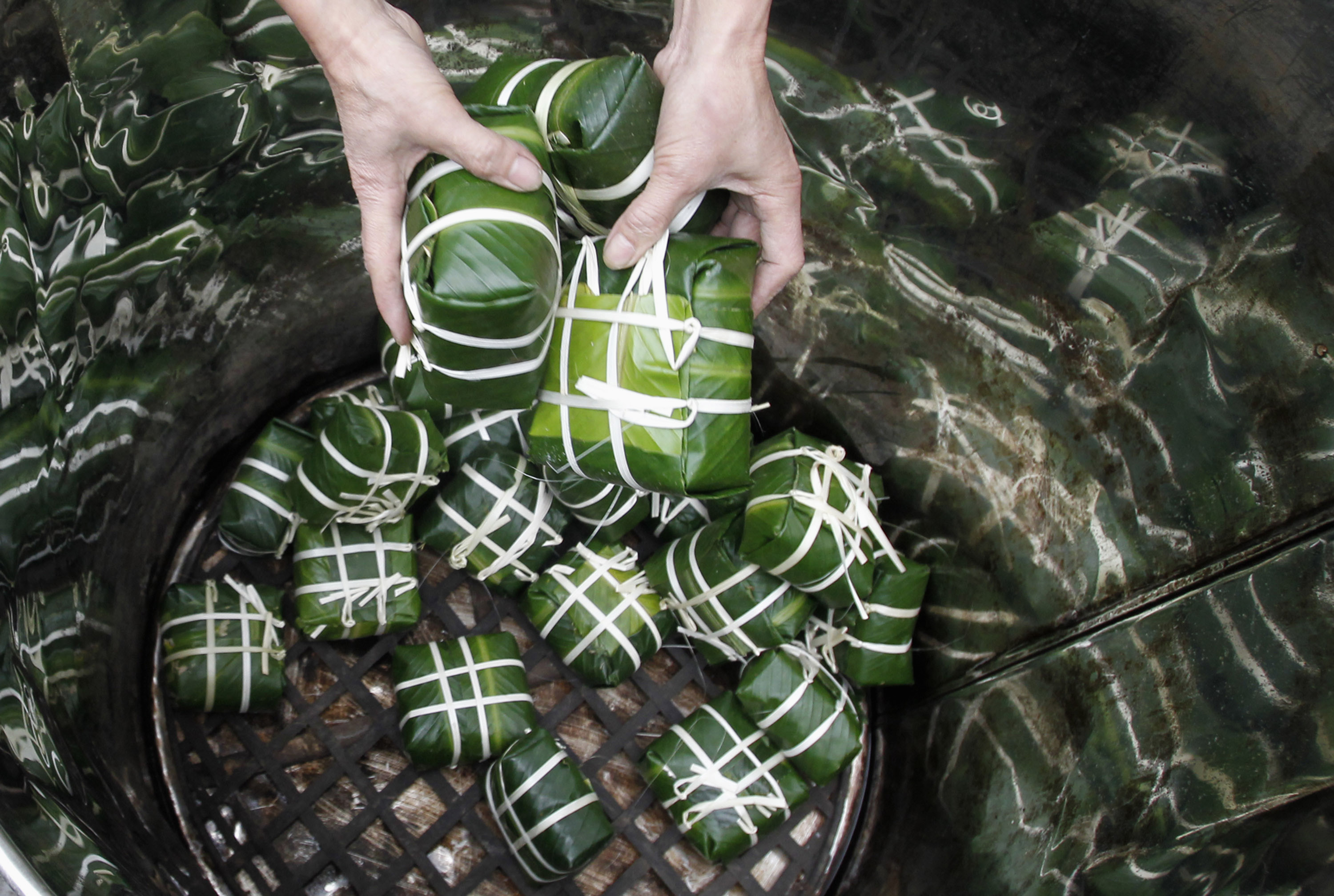 A resident drops Banh Chung or rice cakes to to cook at Tranh Khuc village, outside Hanoi January 14, 2012.