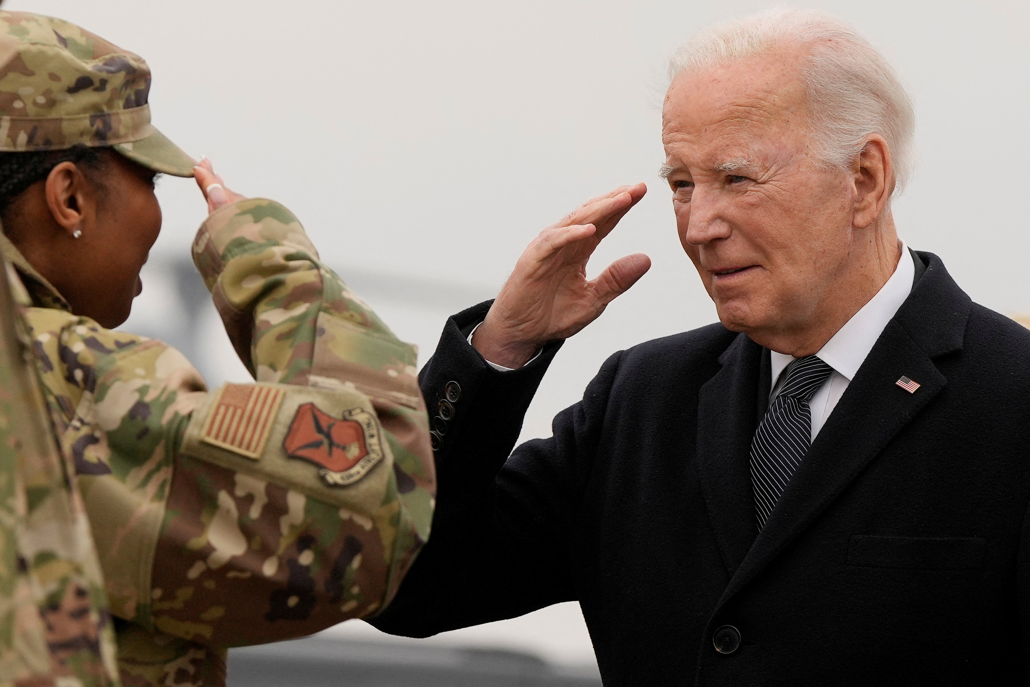 Biden and US soldier in military fatigues exchange army salute