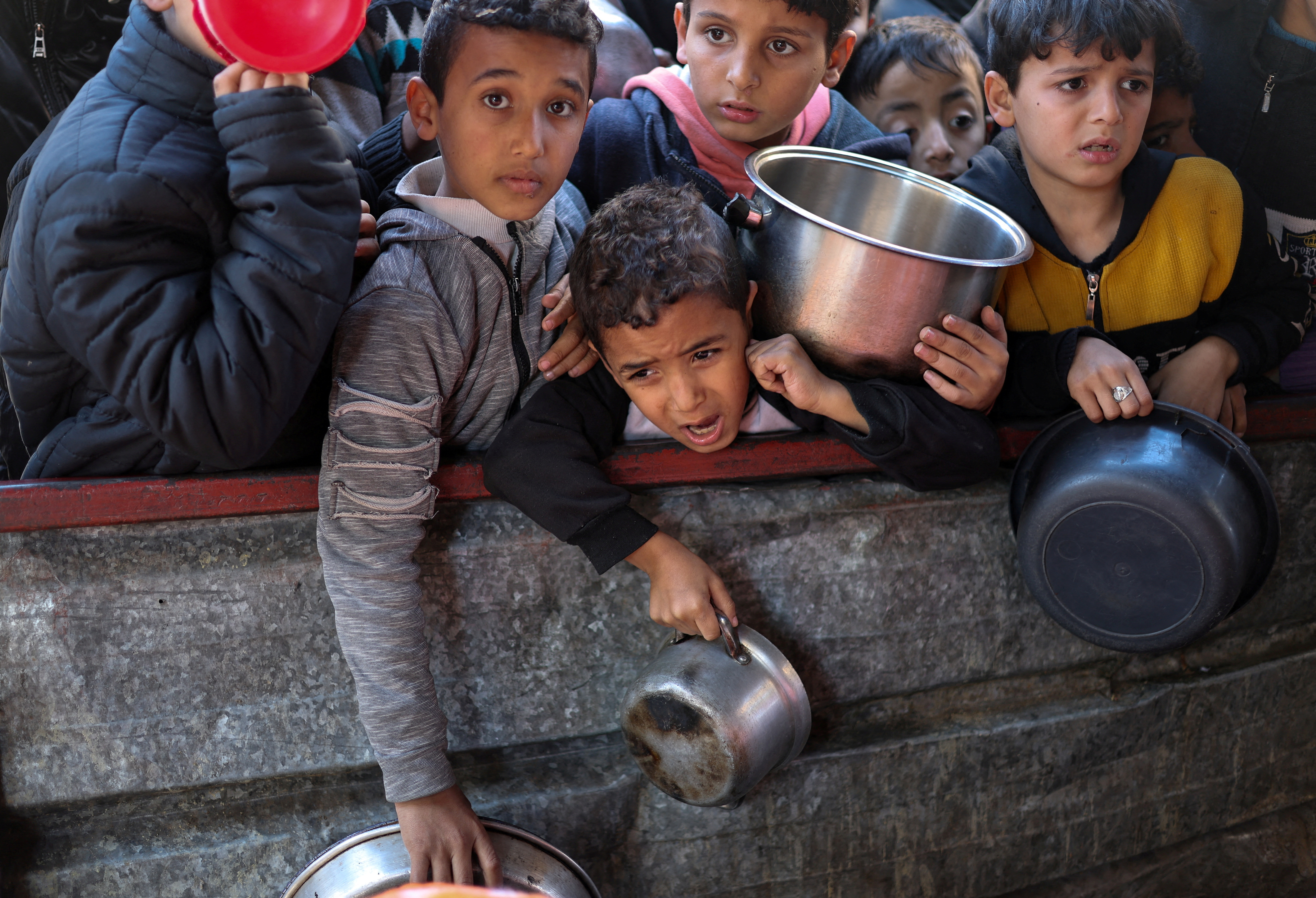 Children carrying pots to receive food