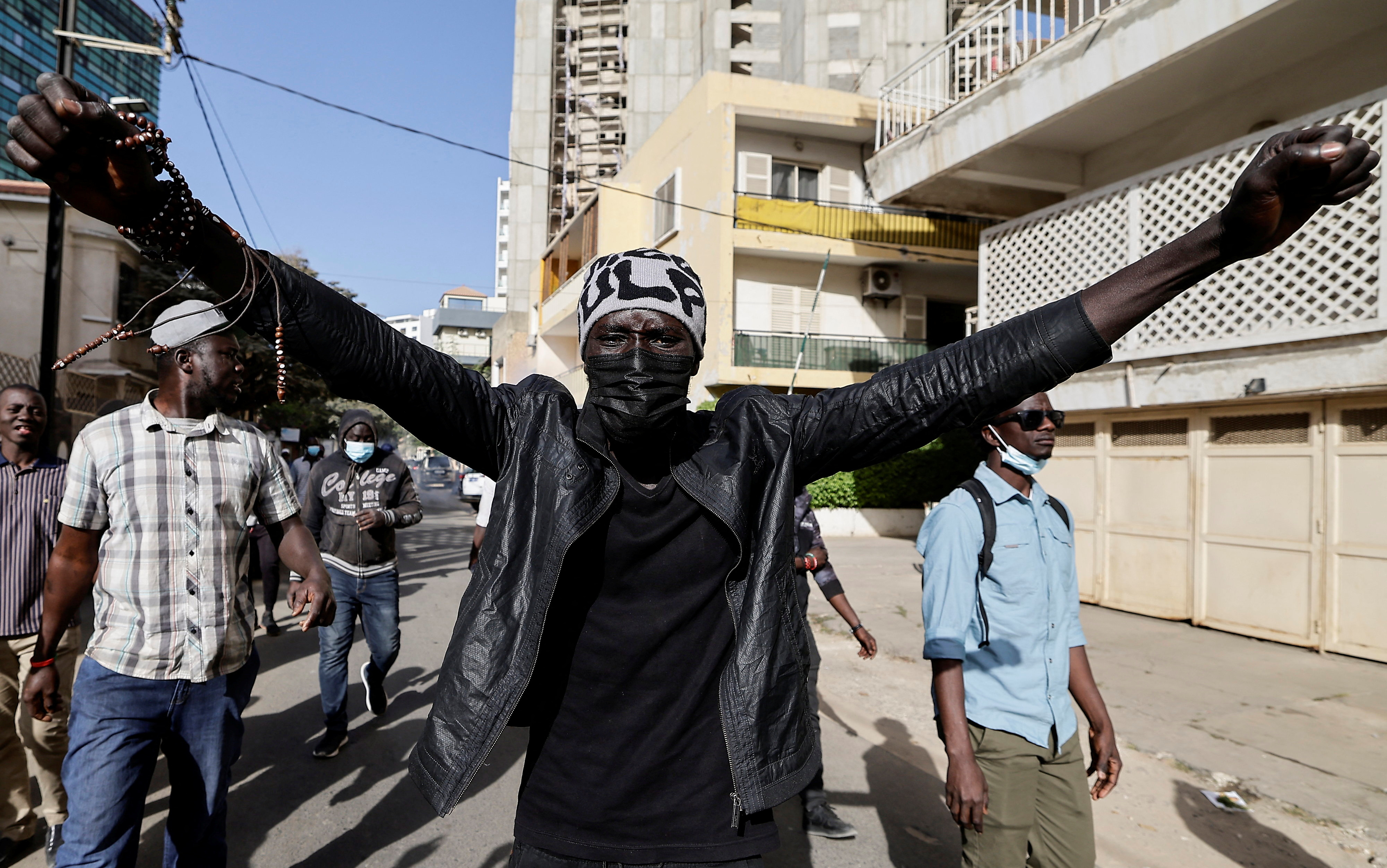 A protester in Dakar, He is holding his arms out as he walks through the street
