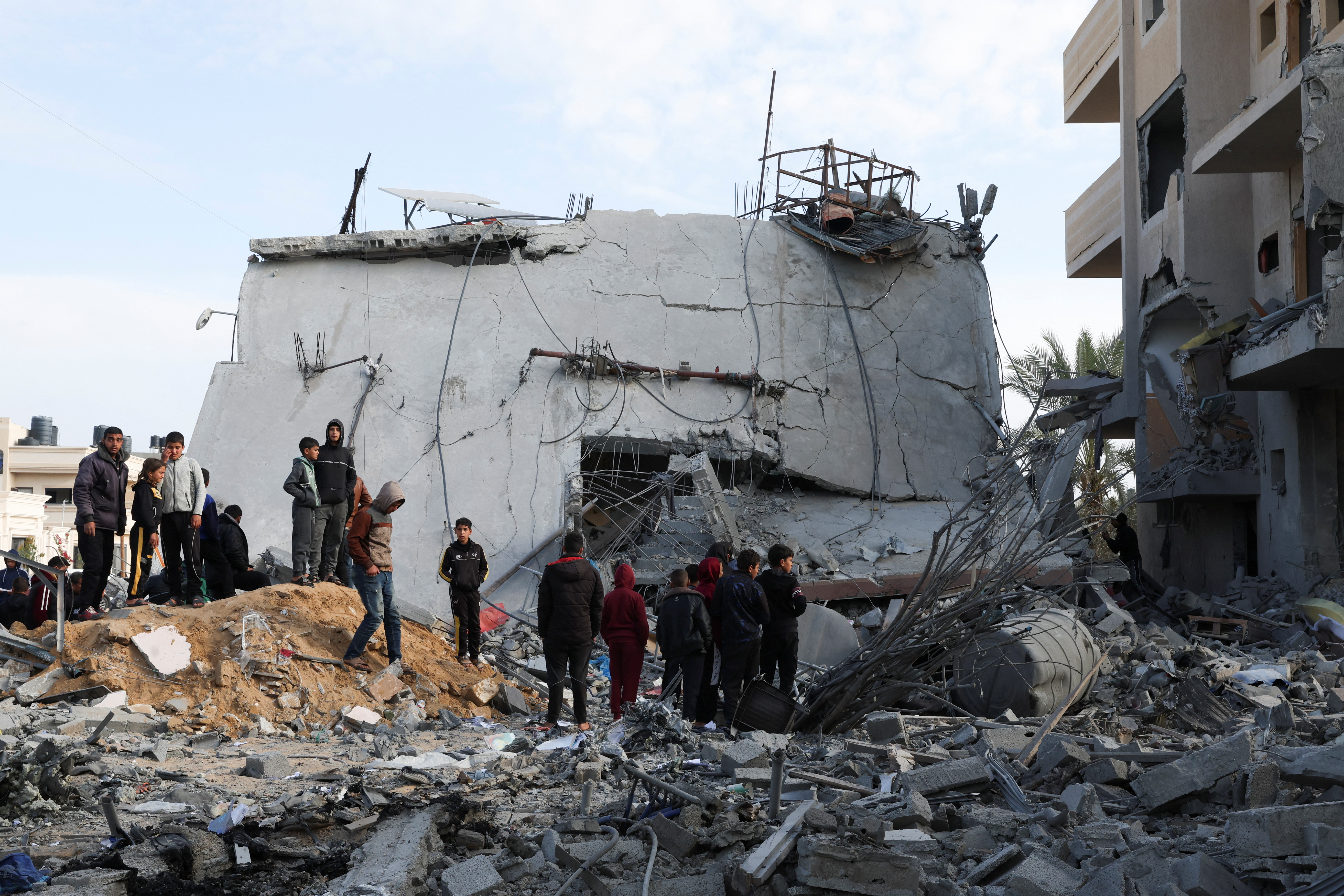 Palestinians gather near a house hit by an Israeli strike, in Rafah in the southern Gaza Strip February 16, 2024. REUTERS/Ibraheem Abu Mustafa