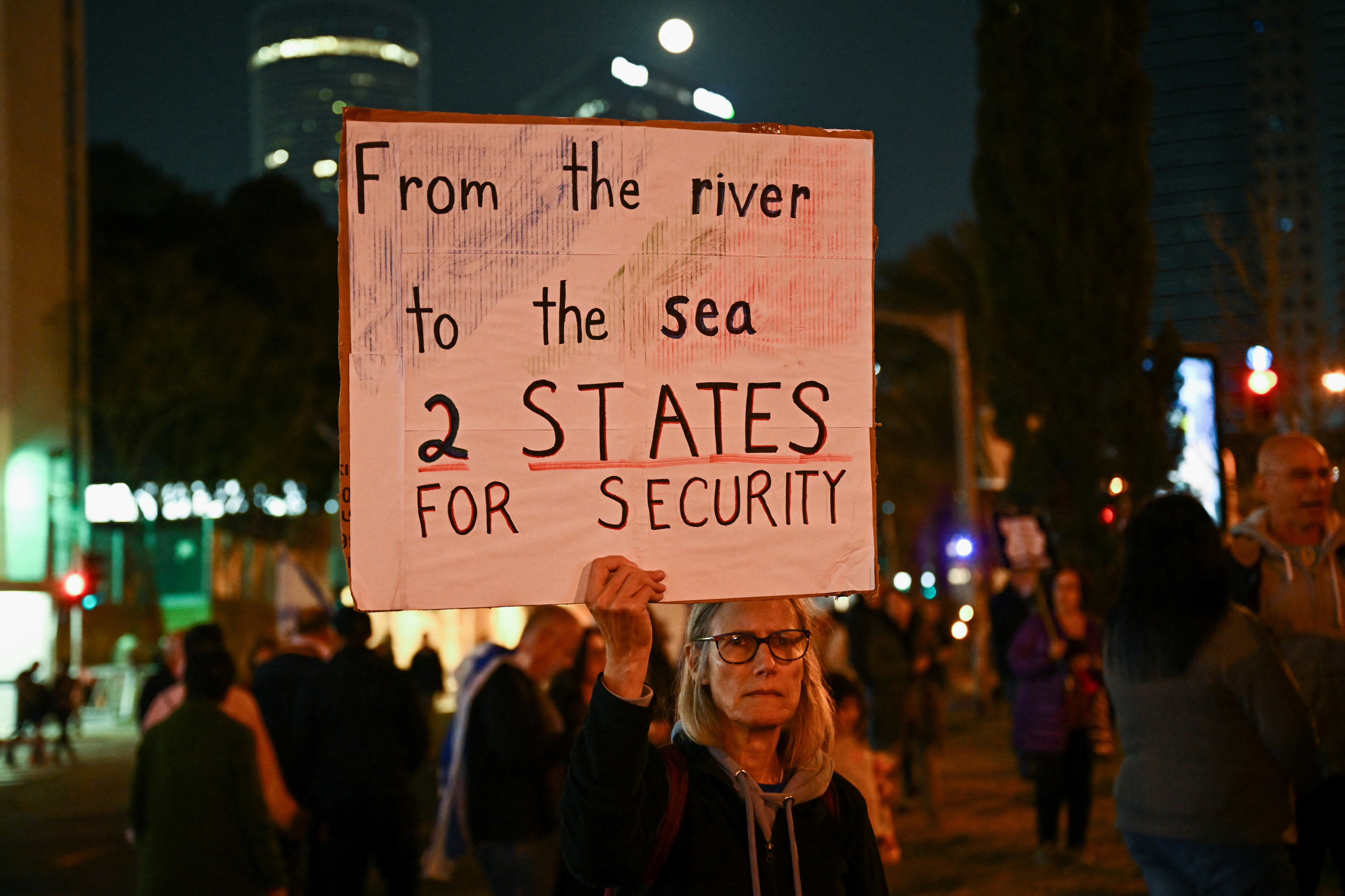 A woman holds a banner as people attend a protest against Israeli Prime Minister Benjamin Netanyahu's government