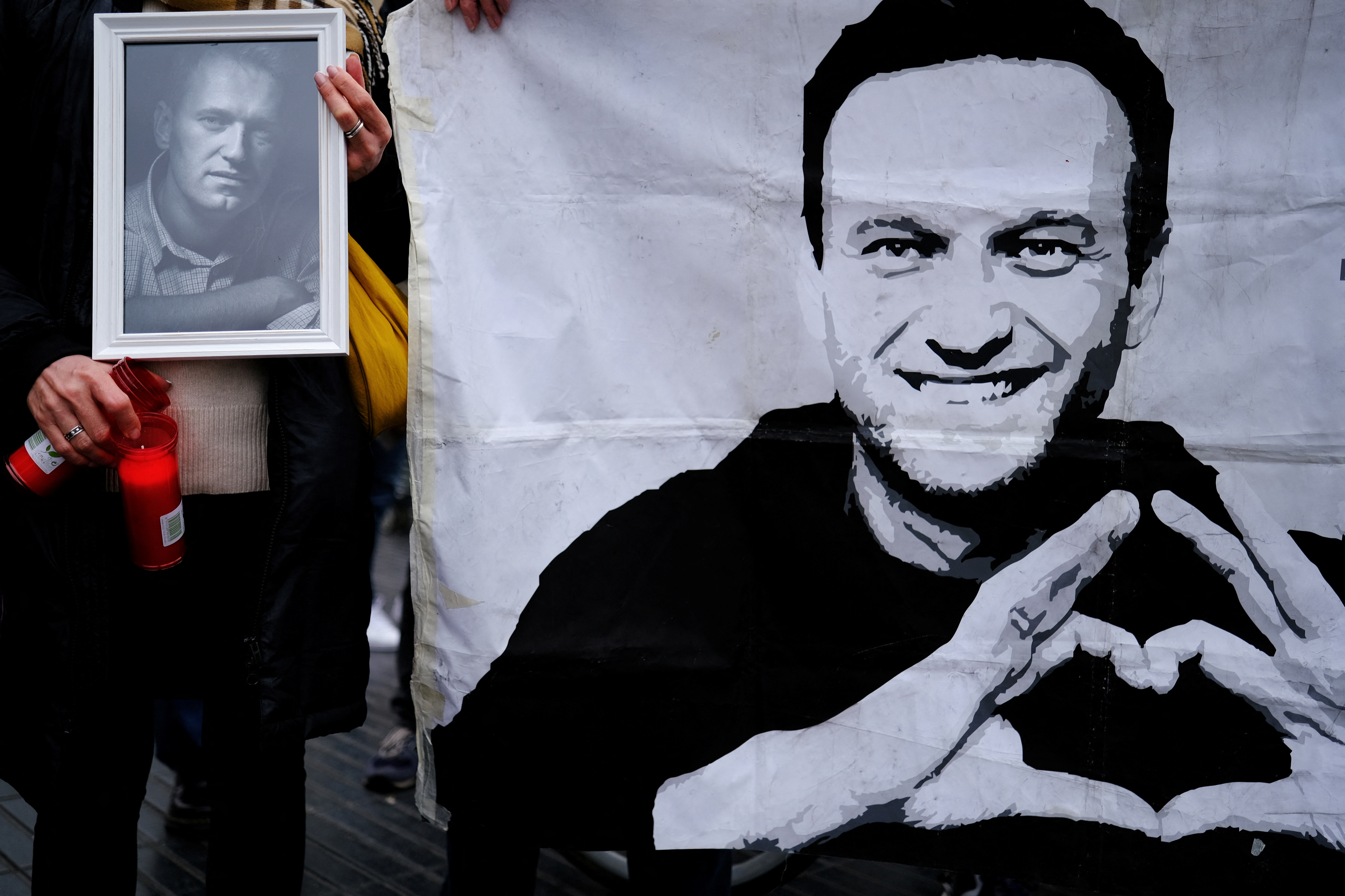 A woman holds candles and a portrait of late Russian opposition leader Alexei Navalny, who died unexpectedly in prison ten days ago, in front of his memorial at Las Ramblas of Barcelona, as people attend a vigil after the body of him was handed to his mother on Saturday in the Arctic city of Salekhard, in Barcelona, Spain, February 25, 2024. REUTERS/Nacho Doce