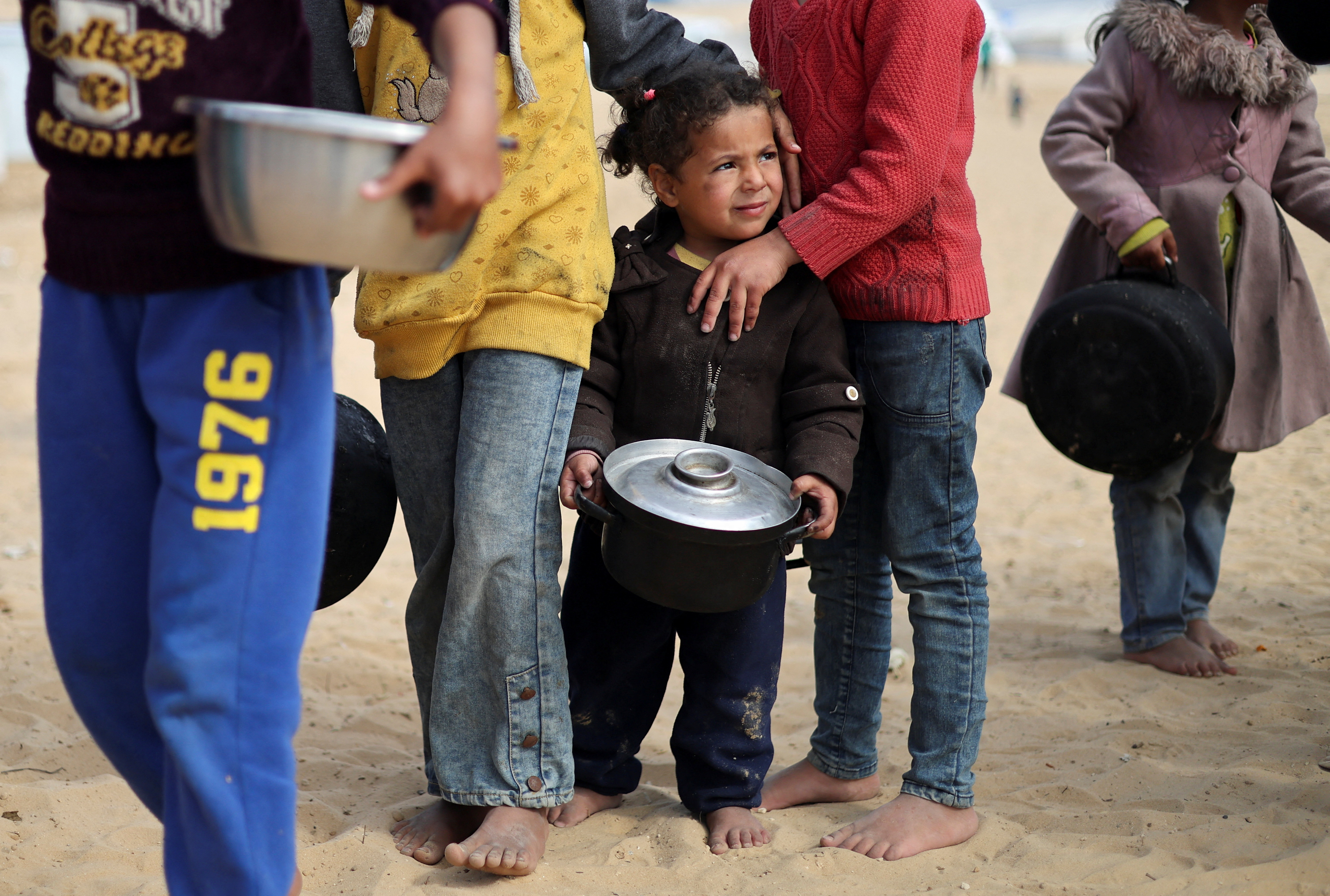 Displaced Palestinian children wait to receive food at a tent camp in Rafah in the southern Gaza Strip, February 27, 2024.