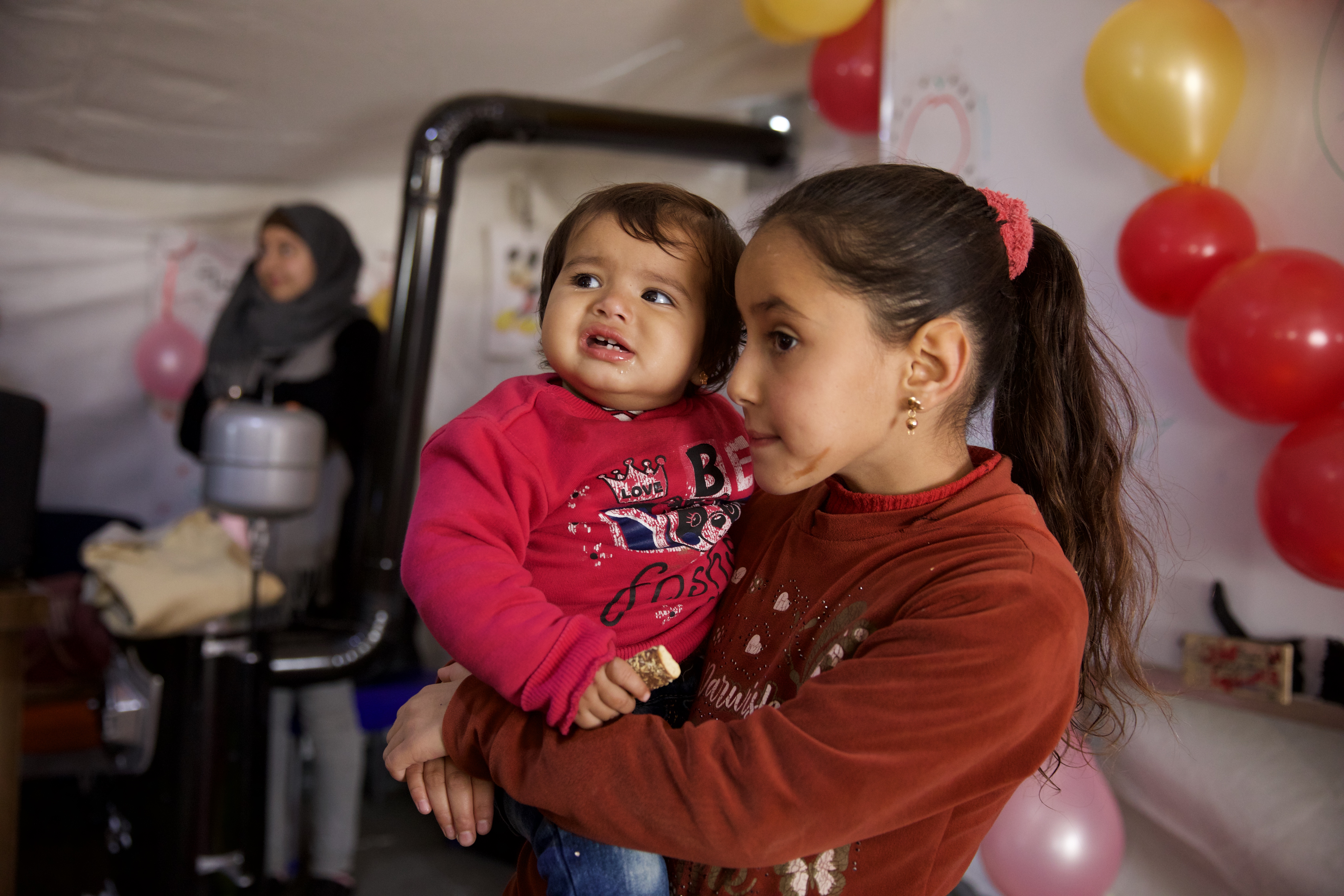 Afraa held by her 'older sister' Doa