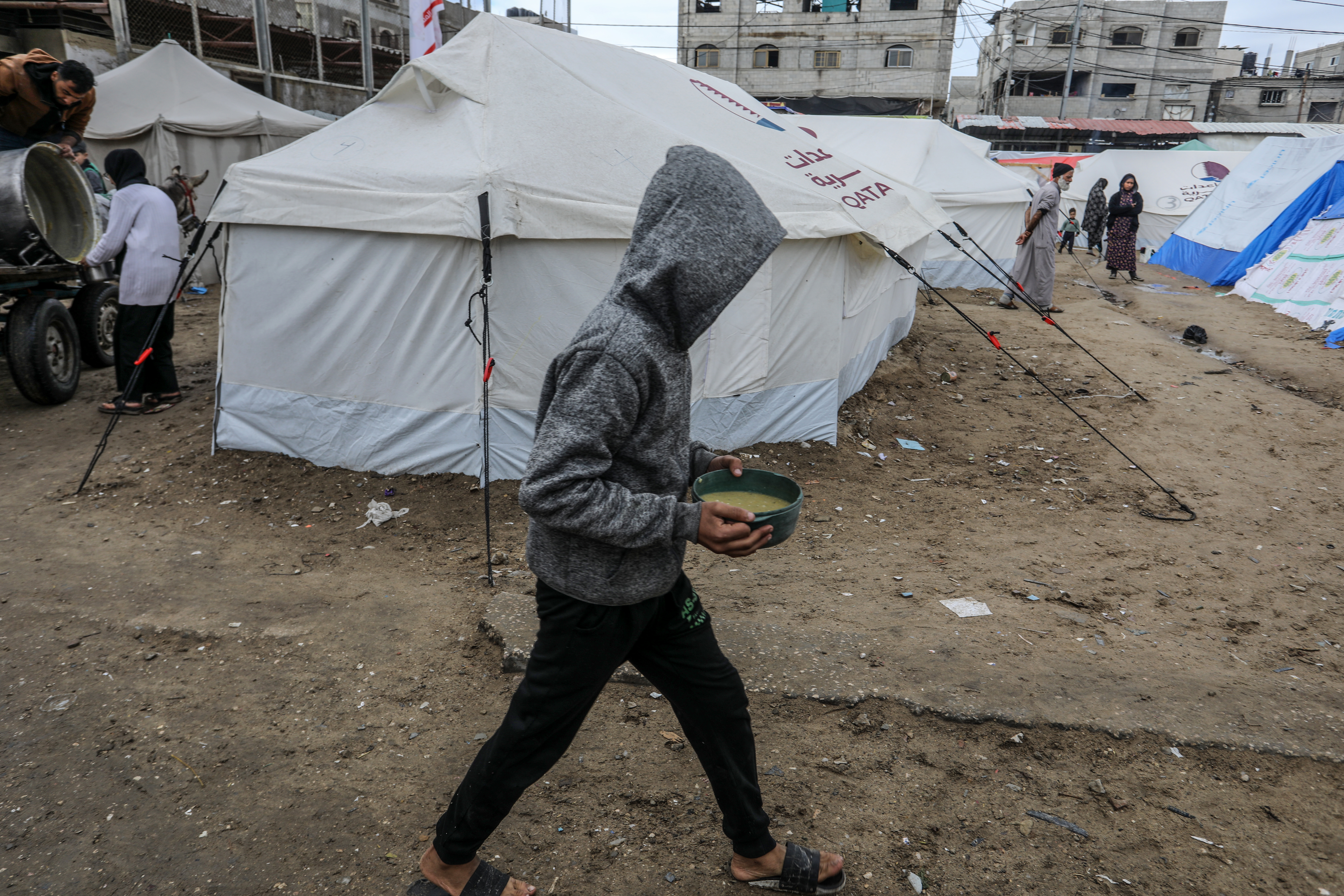 Palestinians holding food filled bowls after food distribution by volunteers of charities as people facing hunger crisis and famine risk due to the Israeli embargo imposed on the territory, in Rafah, Gaza on February 18