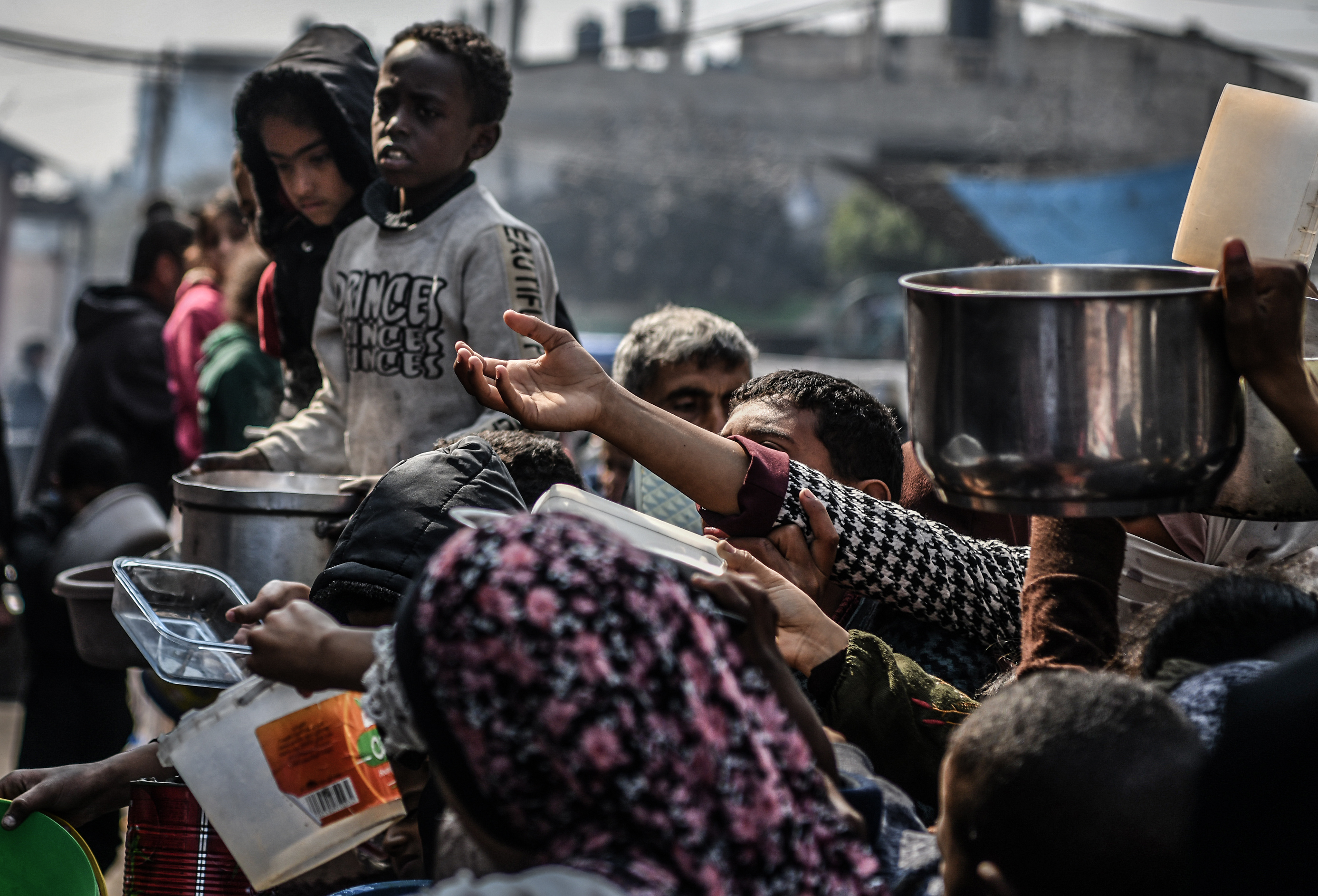 Palestinians hold pots waiting for food