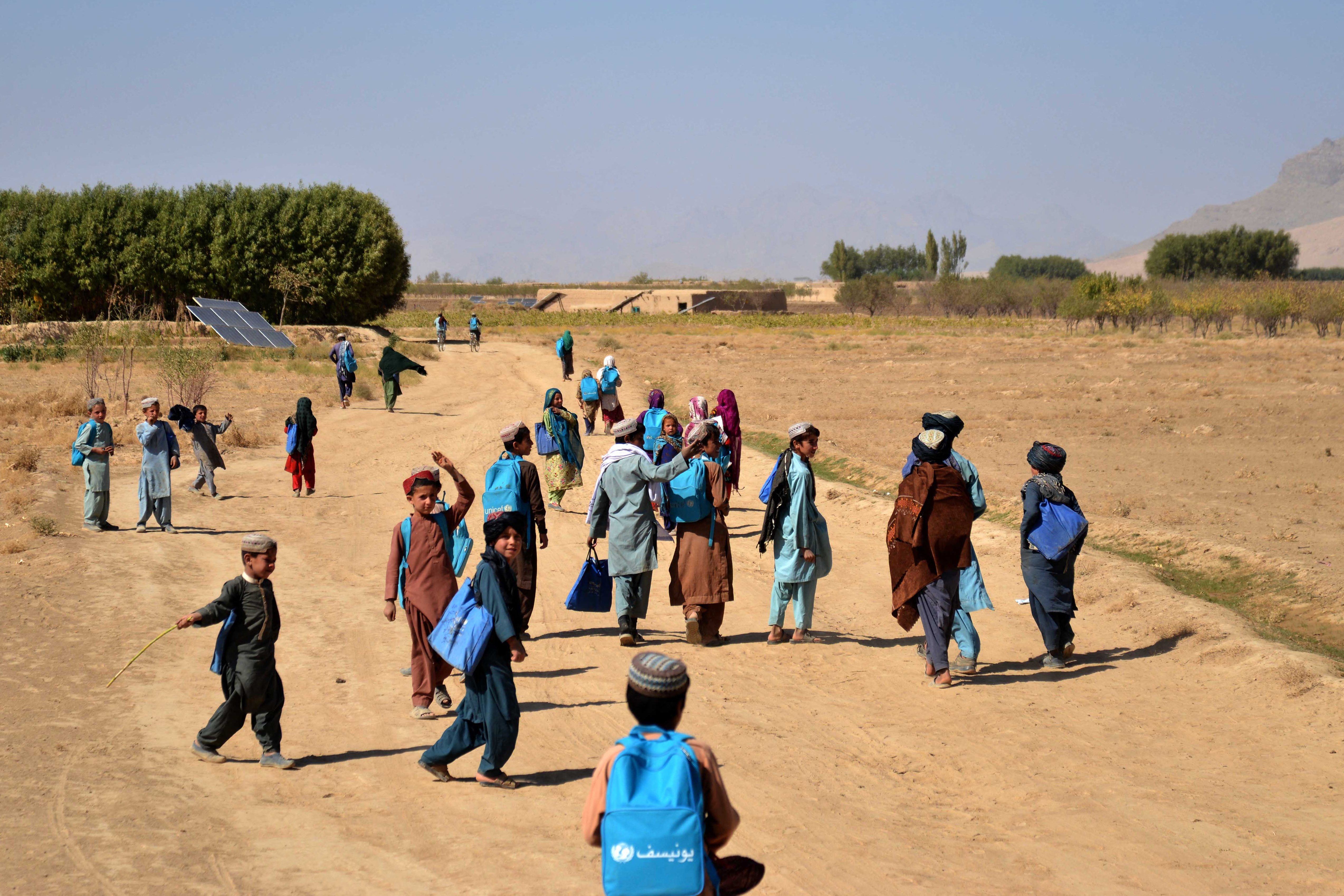 Afghan students make their way home after attending class at an open air school in Zabul on October 24, 2023. (Photo by Sanaullah SEIAM / AFP)