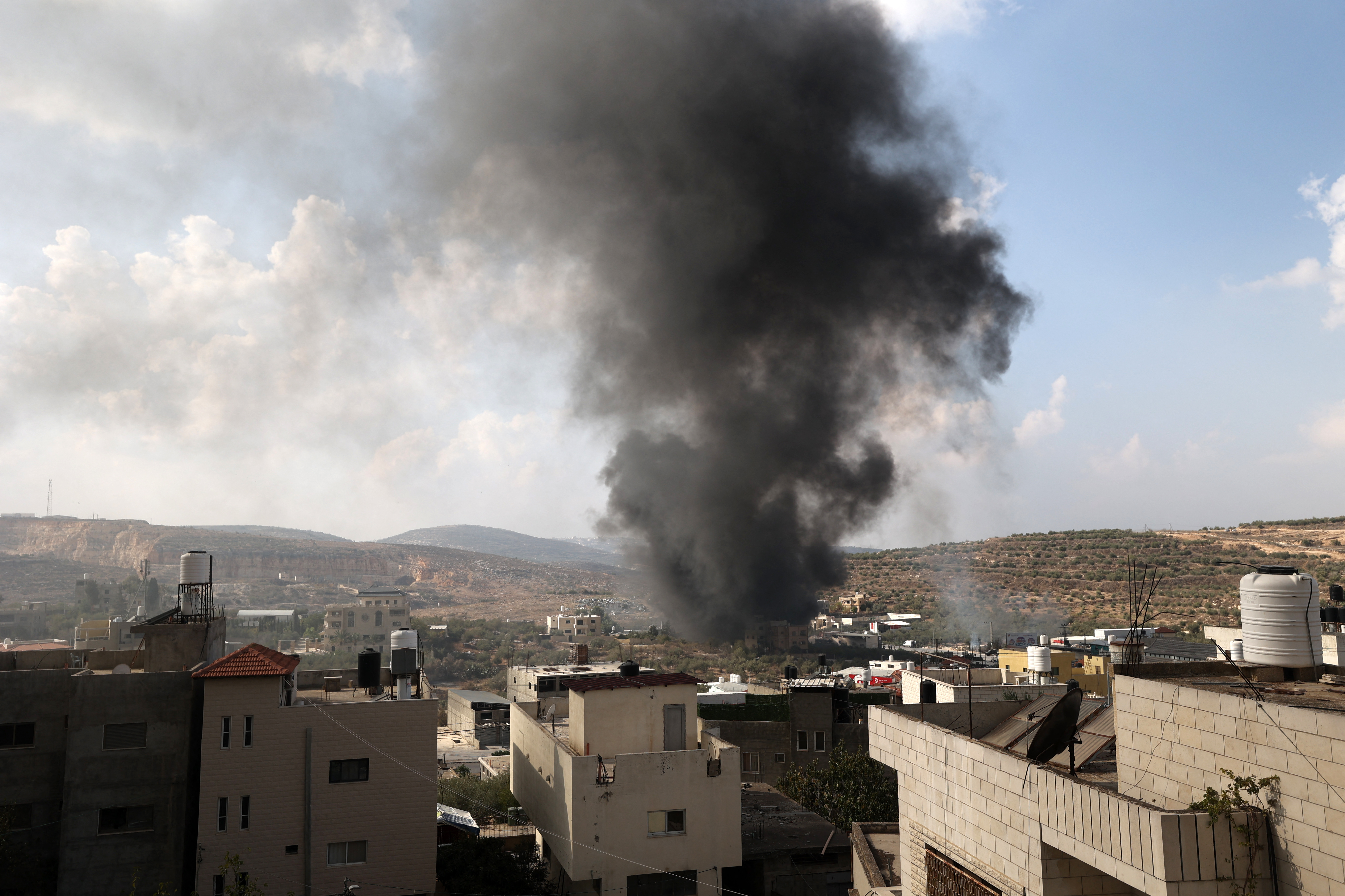 A plume of smoke rises above the town of Deir Sharaf after Jewish settlers from the nearby Einav settlement stormed the occupied West Bank town on November 2, 2023, following the death of an Israeli when his car came under fire. - For several months, the West Bank has seen increasing Israeli army raids, attacks on Palestinians by Israeli settlers and Palestinian assaults against Israeli settlers and security forces. (Photo by Jaafar ASHTIYEH / AFP)